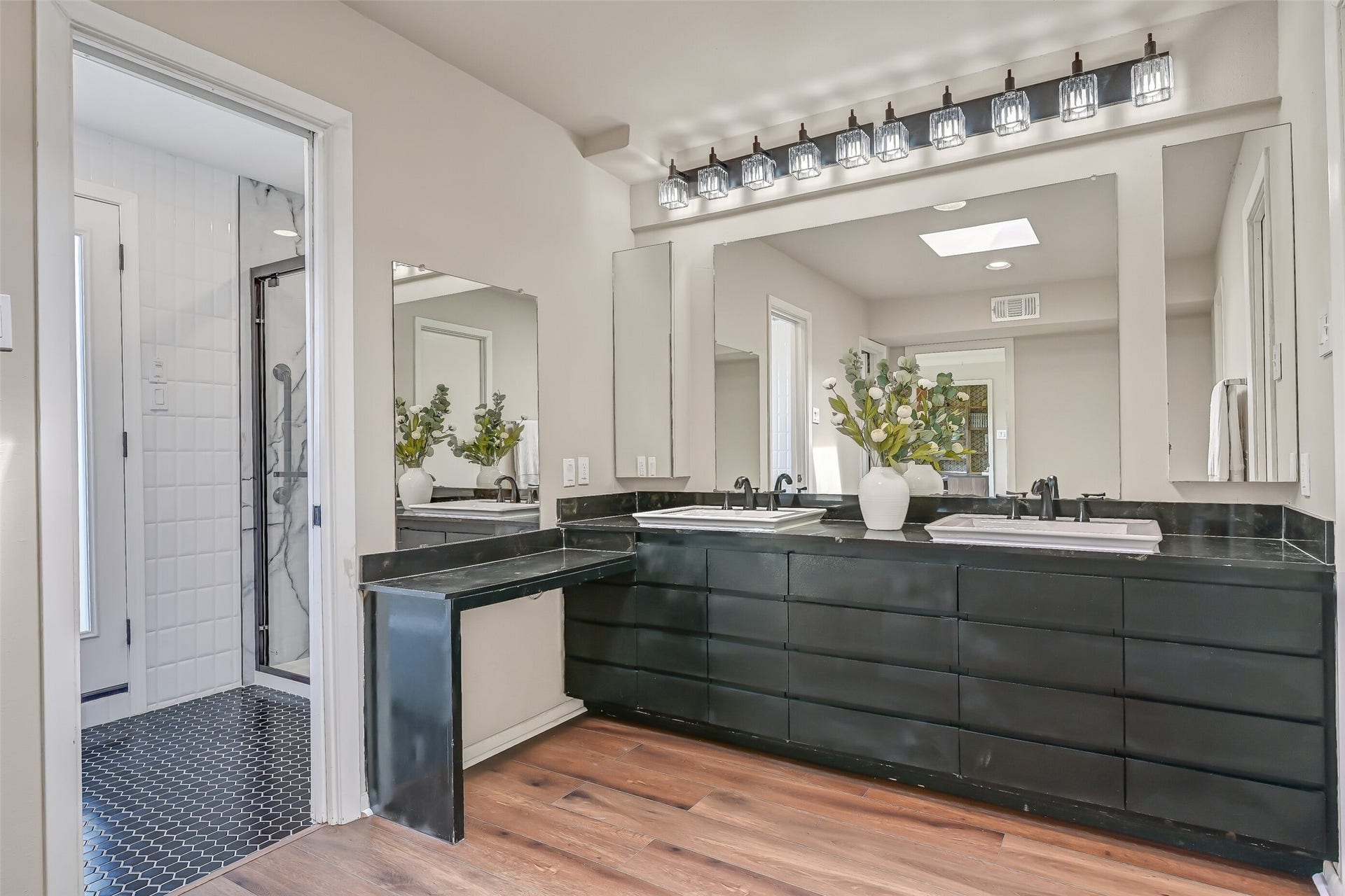 300 Courtlandt Place, Friendswood, TX 77546 The primary bathroom features an expansive dual-sink vanity with dark cabinetry, generous drawer storage, black countertops & contemporary lighting. A separate dressing vanity adds convenience, while the adjoining bathing area includes an updated shower & recently replaced soaking tub.