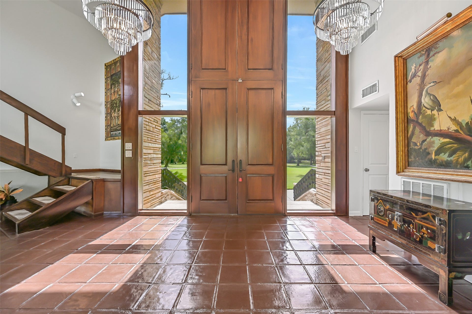 300 Courtlandt Place, Friendswood, TX 77546 Step inside to a dramatic 17' entry with soaring ceilings, two grand chandeliers & a beautiful open-riser staircase leading to the private upstairs primary suite. The home's distinctive contemporary architecture is immediately apparent, with an inviting view into the sunken living room.