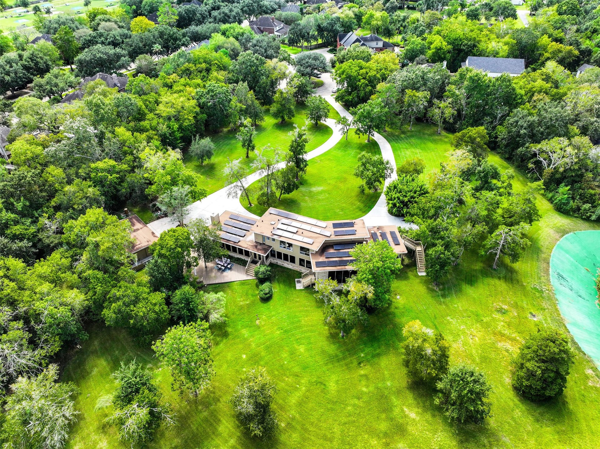 300 Courtlandt Place, Friendswood, TX 77546 A different perspective highlights the home's distinctive rooflines, expansive rear deck & large windows overlooking the property. Mature trees provide a beautiful backdrop, while the open lawn offers abundant space for outdoor recreation, gardening or simply enjoying the grounds.