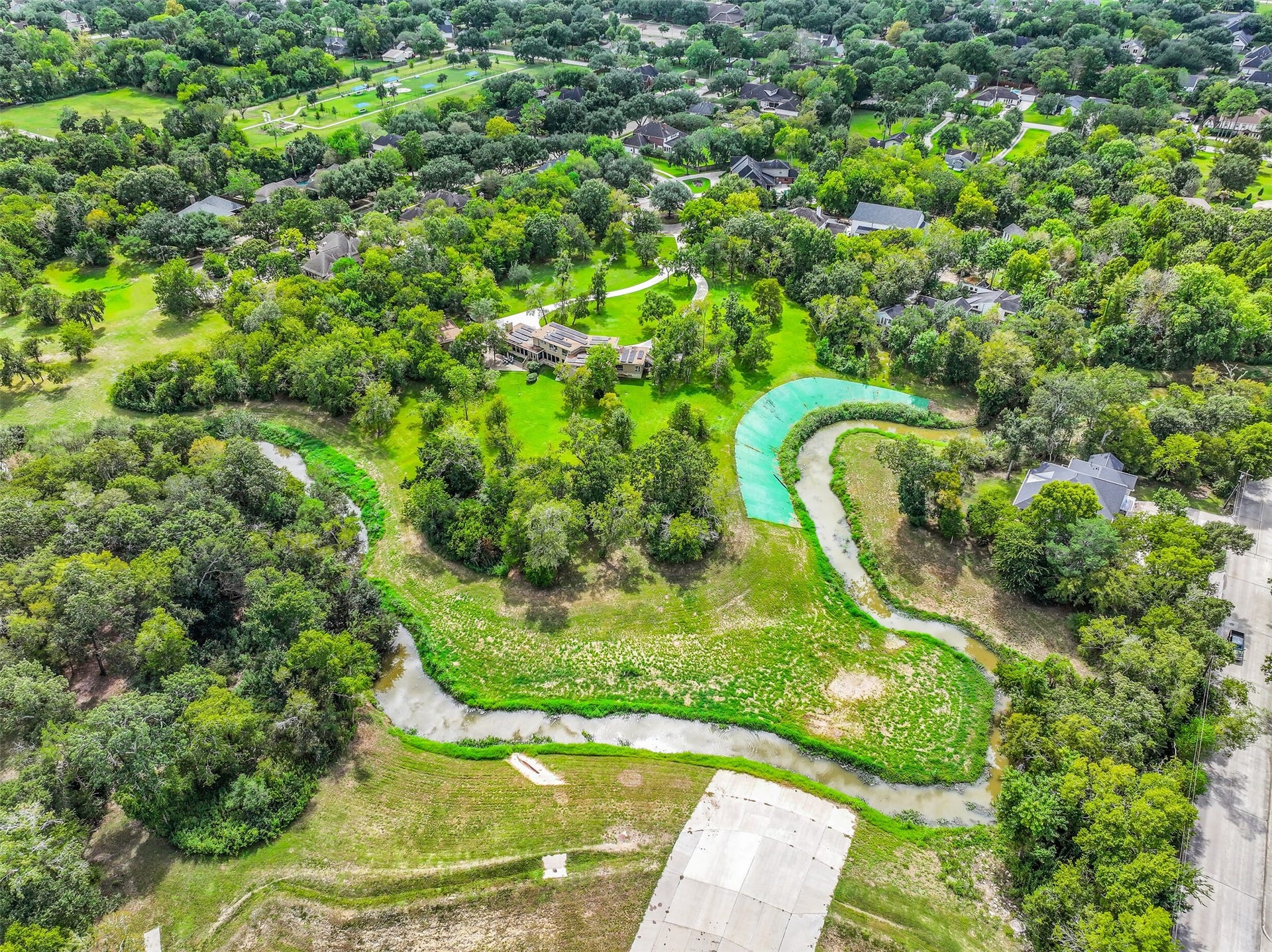 300 Courtlandt Place, Friendswood, TX 77546 A closer aerial reveals the home's distinctive contemporary architecture, extensive circular driveway & detached 2-car garage. The residence sits well removed from the street, surrounded by mature landscaping with generous open space extending across the property's 4.749 acres.