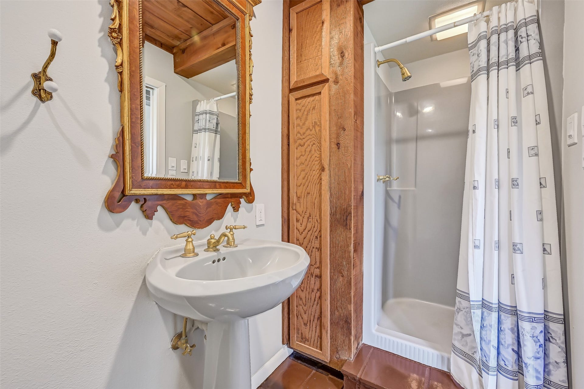 300 Courtlandt Place, Friendswood, TX 77546 Conveniently located near the prefvious bedroom, kitchen & gameroom, this full bathroom features a pedestal sink with gold-tone fixtures, decorative mirror, stand-up shower & distinctive wood cabinetry. Its location makes it easily accessible from the adjoining living spaces.