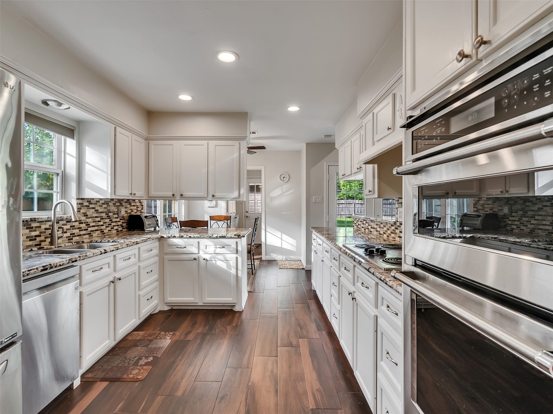 3017 Inwood Drive, Dickinson, TX 77539 This beautiful kitchen features warm wood-look flooring, a stunning glass tile backsplash, and gorgeous granite countertops.