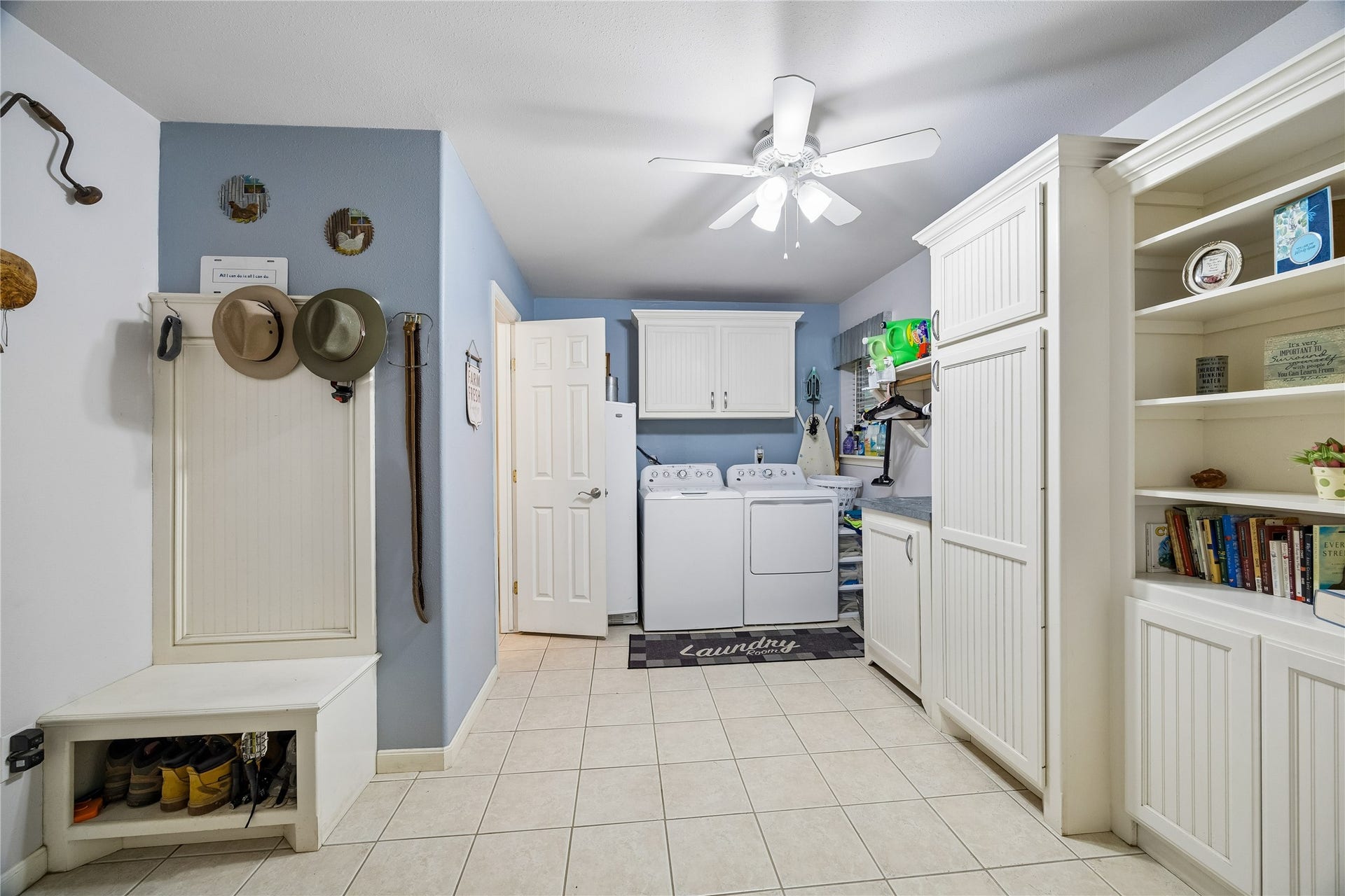 Entering from the three-car carport to the main house, you are welcomed by a highly functional utility zone featuring a convenient half bath, custom built-in cabinets, a built-desk && laundry area