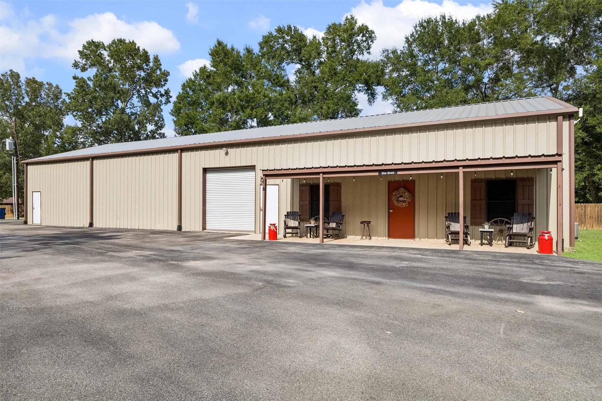 The grand workshop, featuring two 10x12 roll-up doors, a convenient half bath, and a clever partitioned layout. One side remains a highly functional workspace, while the other has been transformed into a fully finished entertainment room with half bath that opens directly onto a spacious covered patioperfect for hosting guests or relaxing after a project.