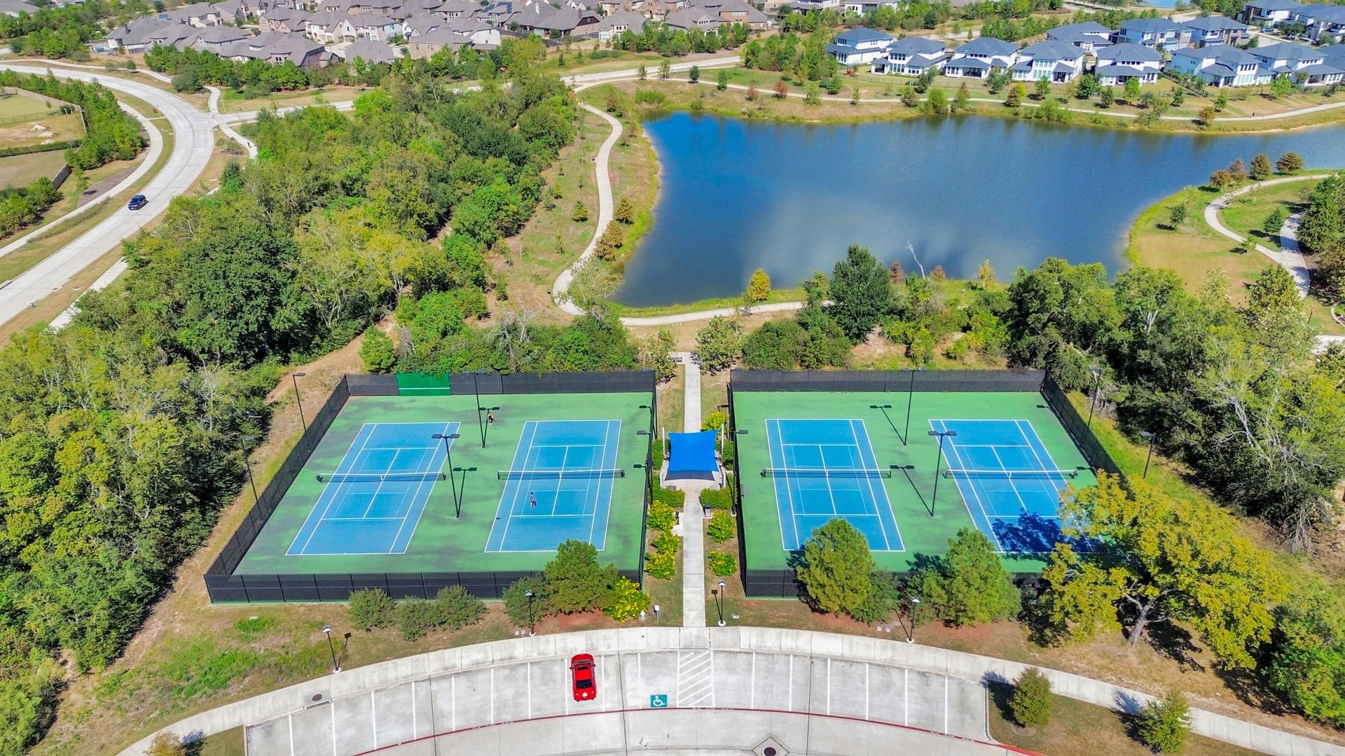 16506 Texas Hill Country Rd, Cypress, TX 77433 The aerial view highlights the community tennis courts, showcasing their well-maintained surfaces and strategic layout within the neighborhood, perfect for recreational play.