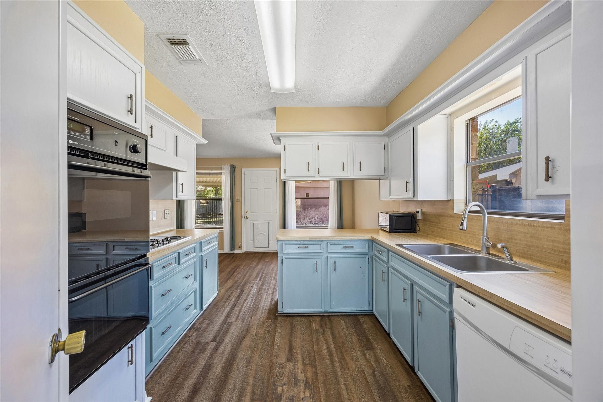 10110 Sagemill Drive, Houston, TX 77089 Bright and inviting kitchen with pastel blue cabinets, ample counter space, featuring large windows that fill the room with natural light.