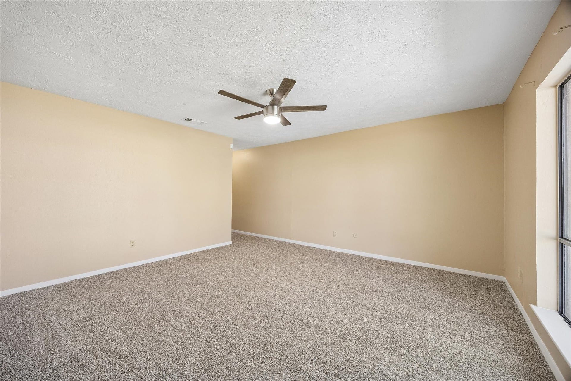 10110 Sagemill Drive, Houston, TX 77089 Spacious living area with neutral-toned walls, plush carpeting, and a modern ceiling fan, offering ample natural light through large windows.
