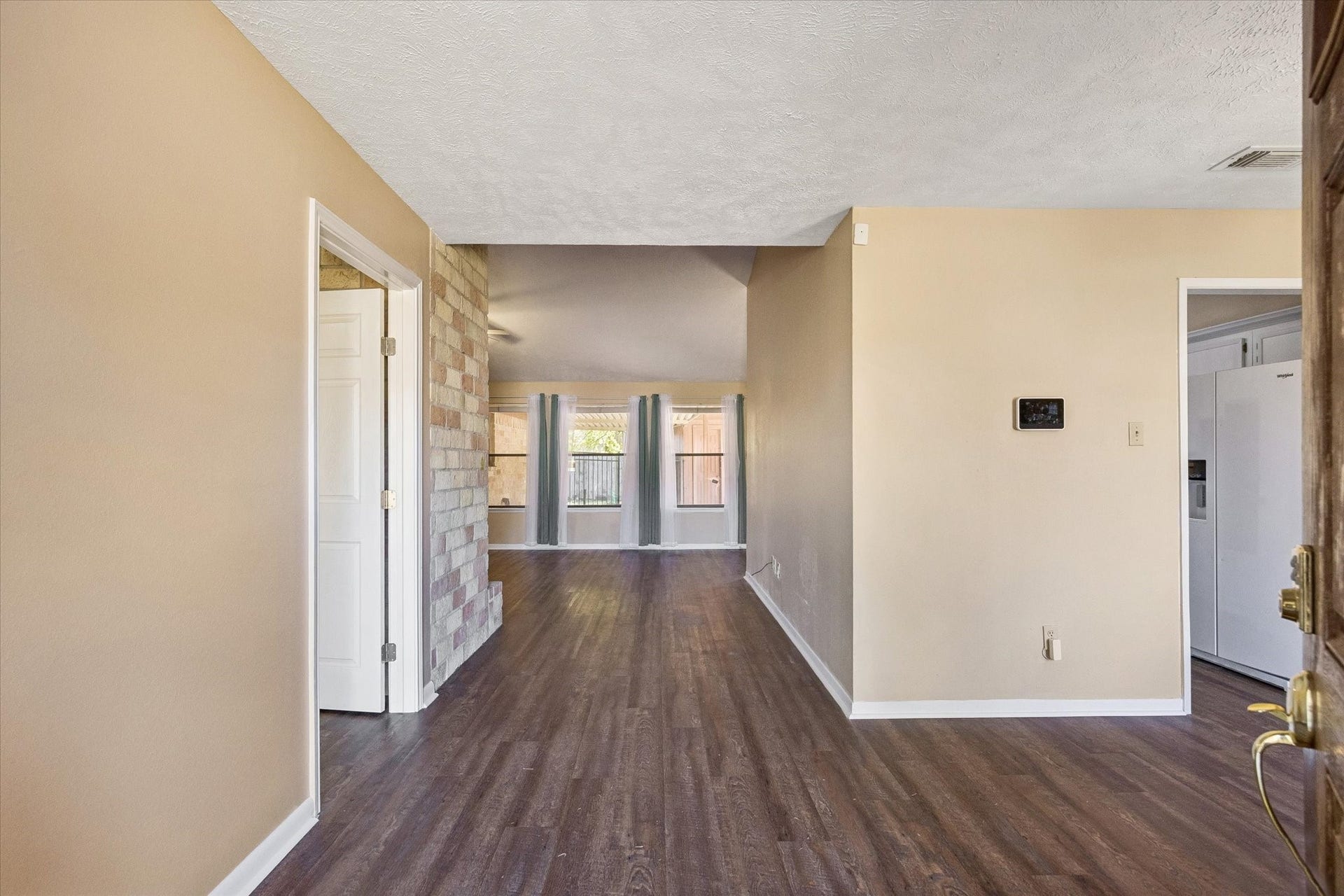 10110 Sagemill Drive, Houston, TX 77089 Inviting entryway with warm-toned walls and rich flooring, leading to a bright living area enhanced by large windows and a stone accent wall.