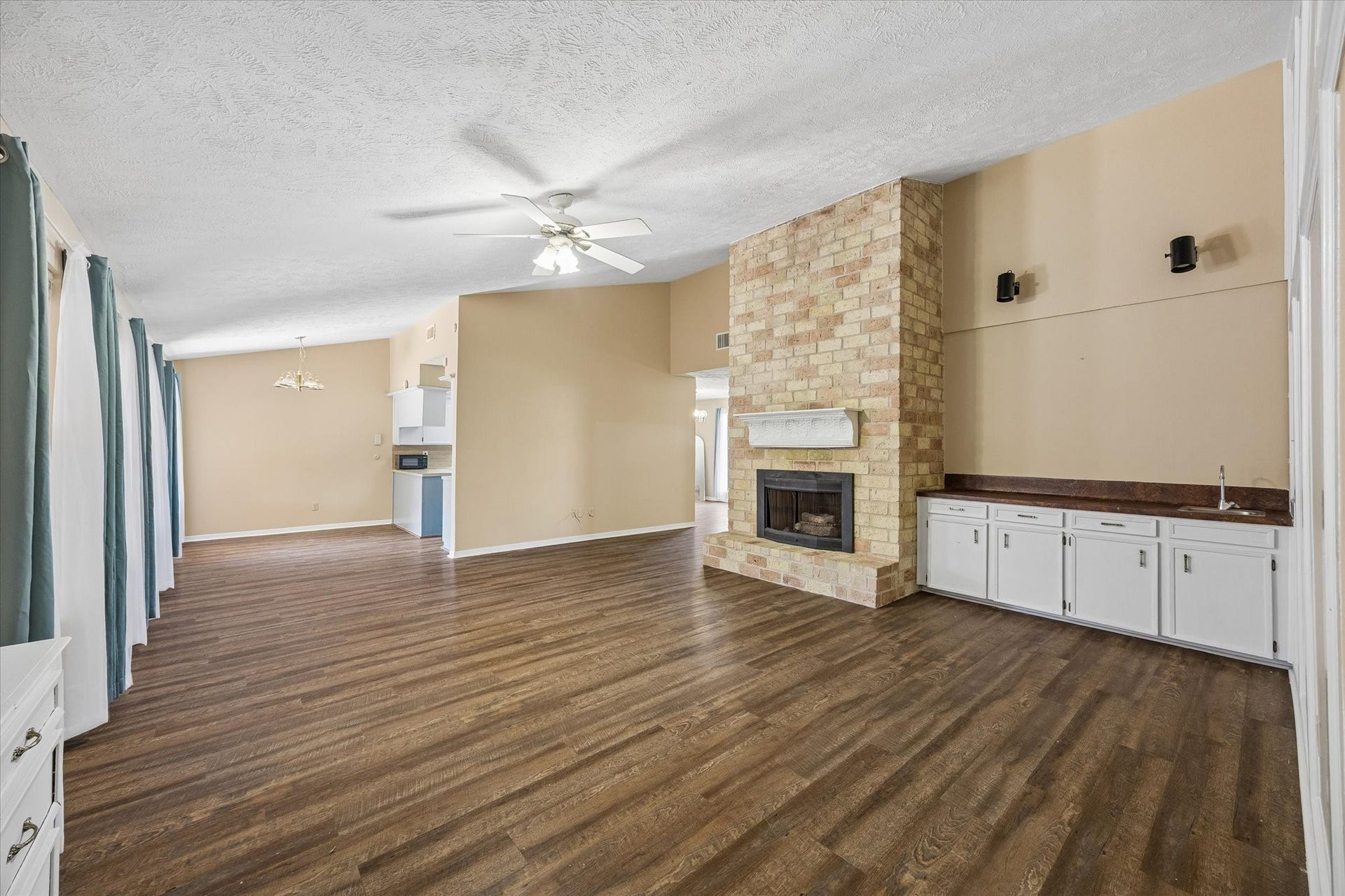 10110 Sagemill Drive, Houston, TX 77089 Spacious open living area featuring a charming brick fireplace, and abundant natural light from expansive windows. The room offers a seamless flow to the dining area and kitchen, ideal for entertaining.