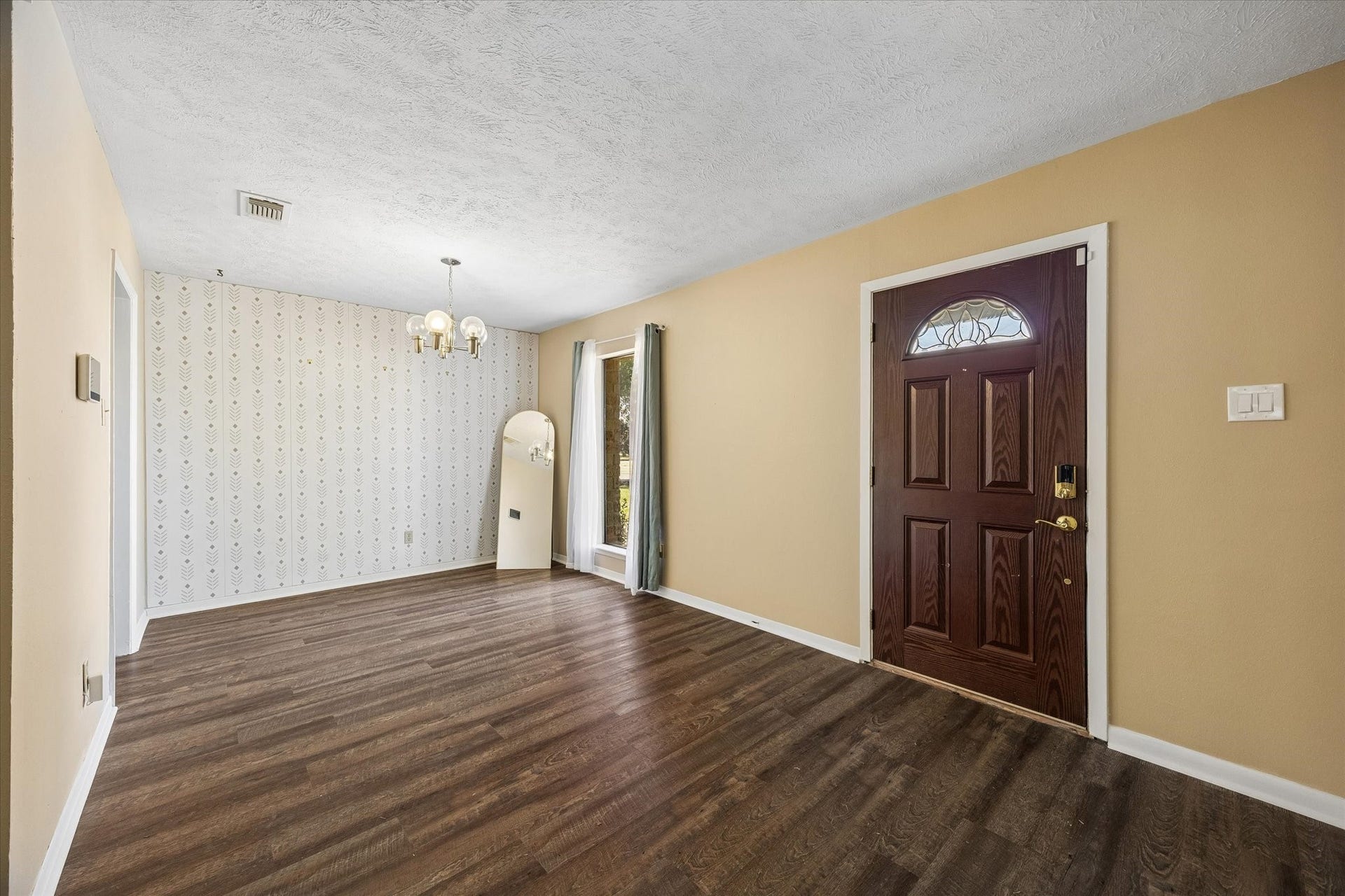 10110 Sagemill Drive, Houston, TX 77089 Inviting entryway with rich flooring, a stylish dark wood front door, and a cozy dining area adorned with a classic wallpaper accent.