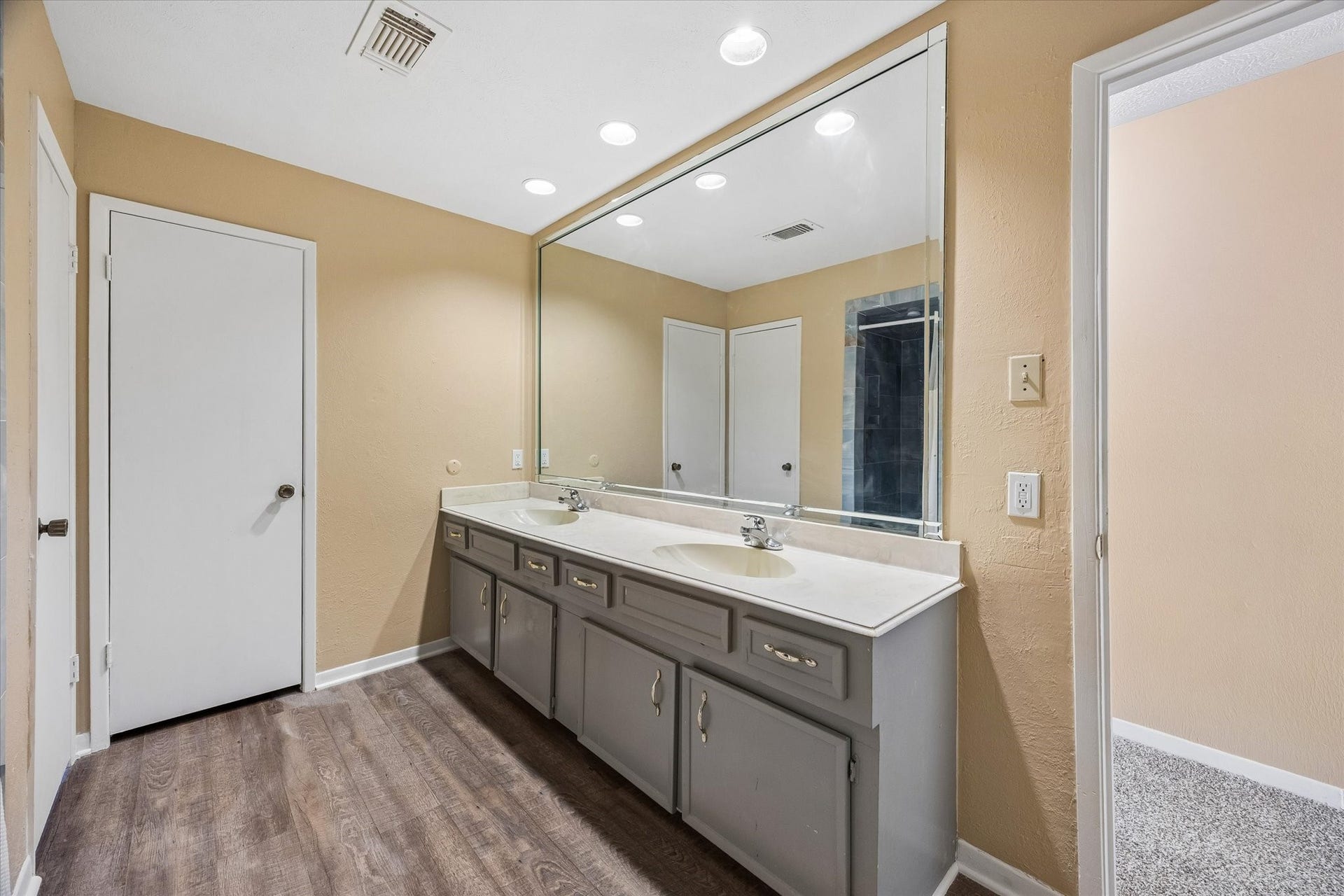10110 Sagemill Drive, Houston, TX 77089 Spacious bathroom featuring a large mirror, sleek vanity with dual sinks, and elegant wood flooring, providing a modern and functional space.