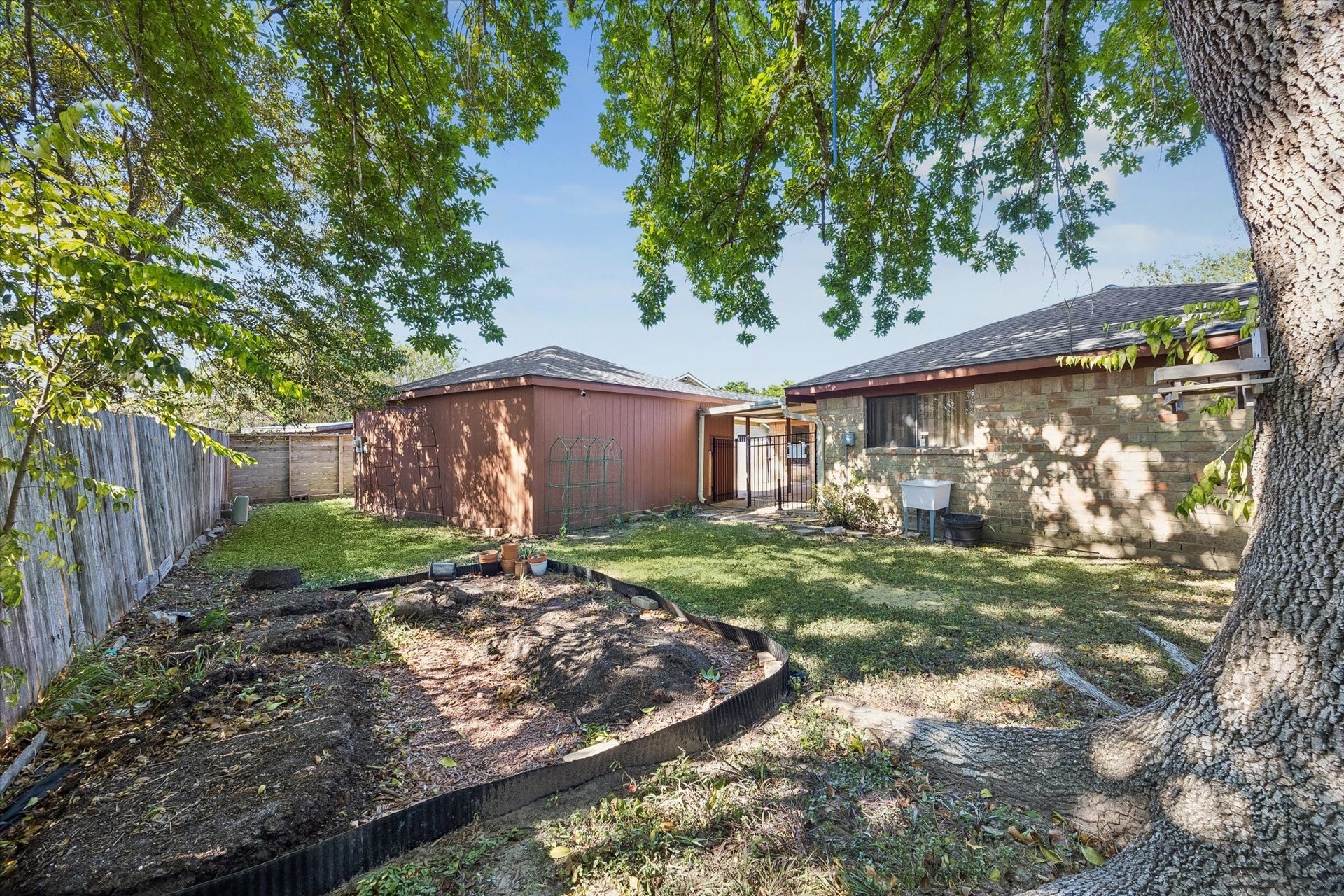 10110 Sagemill Drive, Houston, TX 77089 Charming backyard oasis with mature trees, a cozy patio area, and a spacious lawn perfect for gardening or relaxation.