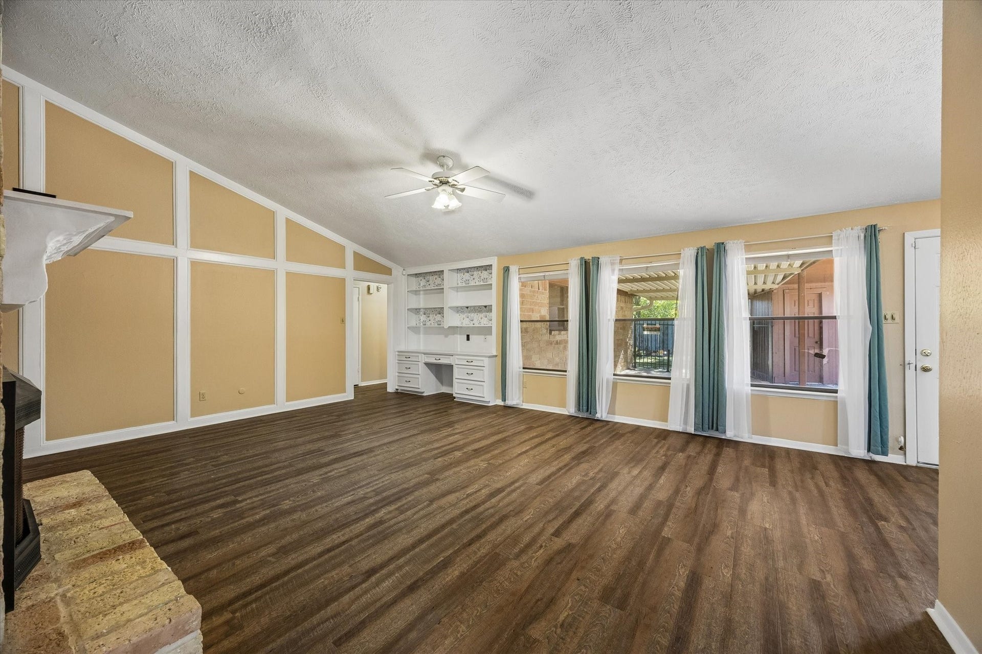 10110 Sagemill Drive, Houston, TX 77089 Spacious living room featuring large windows with stylish curtains offering ample natural light, built-in shelving, and a cozy fireplace, perfect for family gatherings.