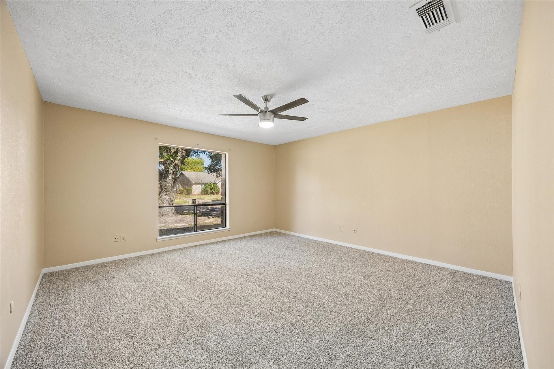 10110 Sagemill Drive, Houston, TX 77089 Spacious bedroom with neutral walls, plush carpet, a modern ceiling fan, and a large window offering natural light.