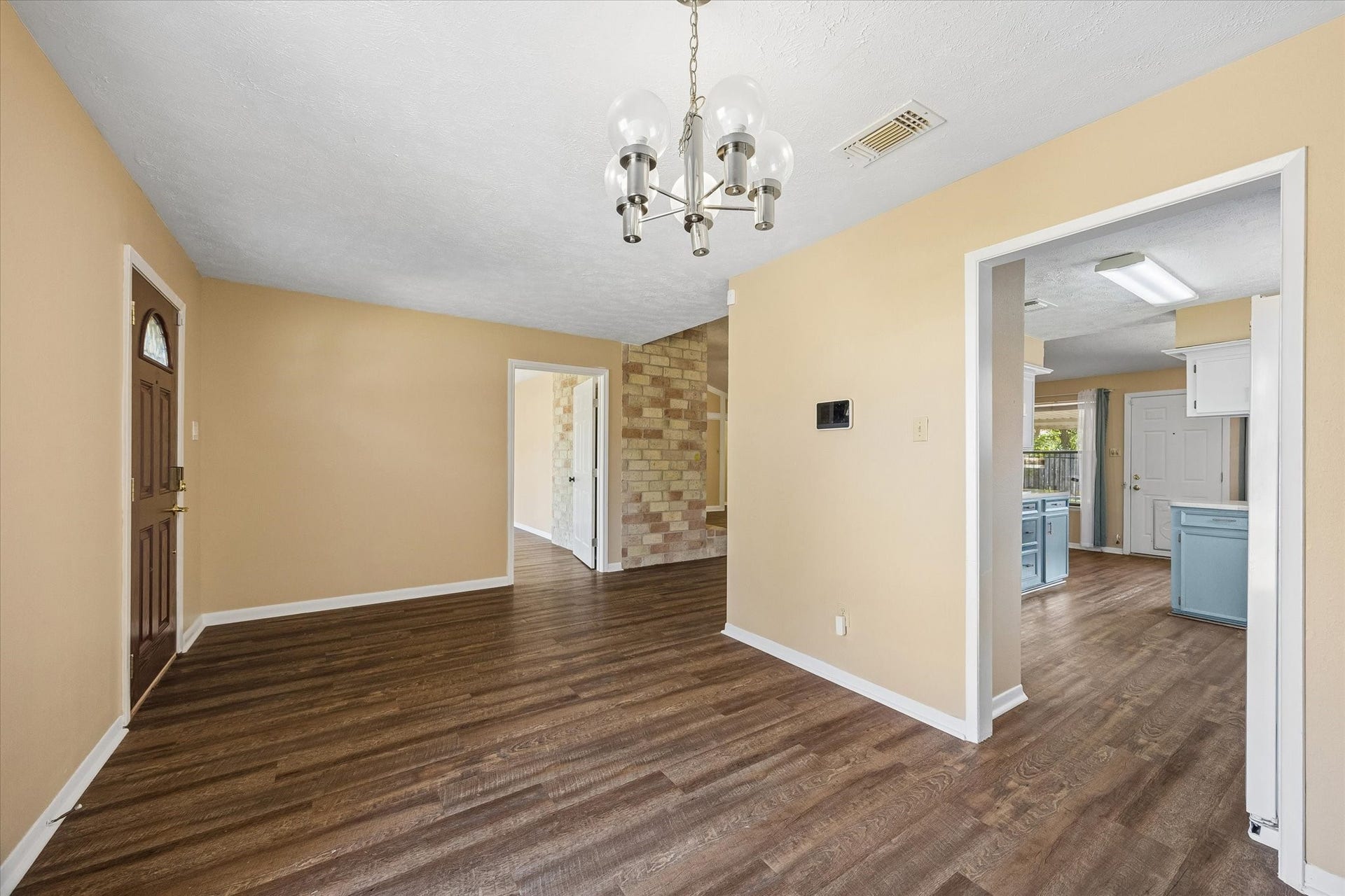 10110 Sagemill Drive, Houston, TX 77089 Charming entryway with warm wood floors and neutral walls, leading to a bright, spacious kitchen.