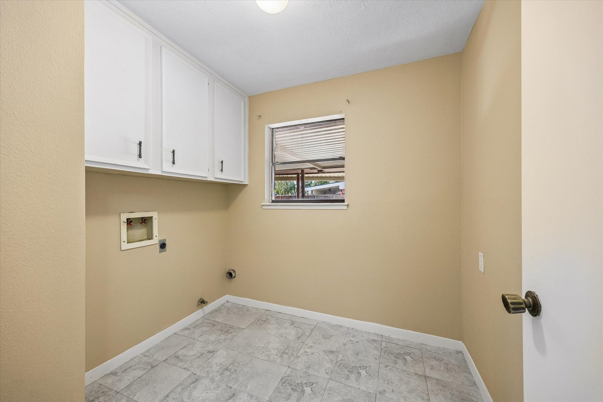 10110 Sagemill Drive, Houston, TX 77089 Bright laundry room with ample cabinet storage, a window for natural light, and tiled flooring for easy maintenance.