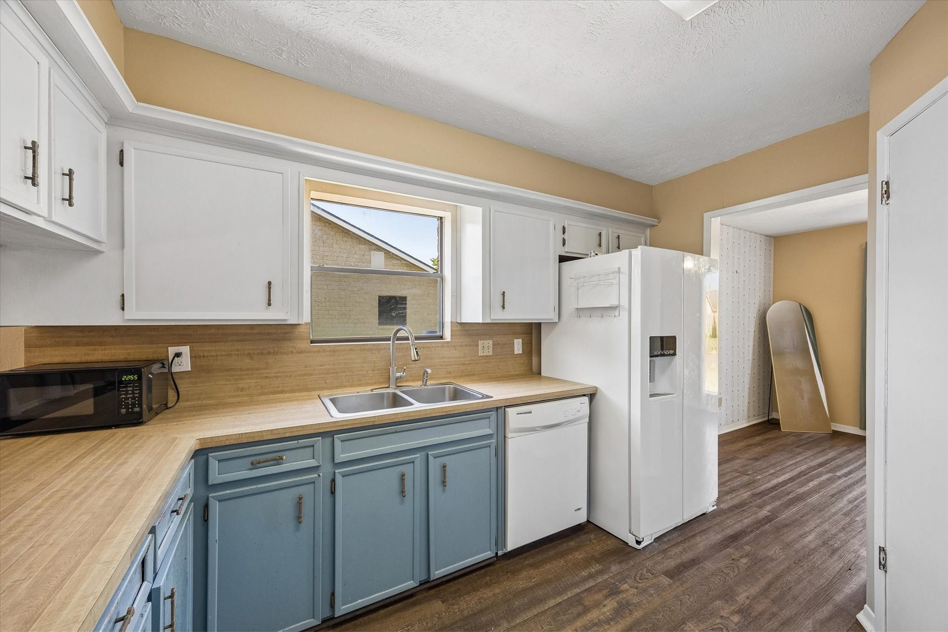 10110 Sagemill Drive, Houston, TX 77089 Charming kitchen with two-tone cabinetry, sleek countertops, and a large window providing natural light. Features include a double sink, dishwasher, and spacious fridge, perfect for culinary enthusiasts.