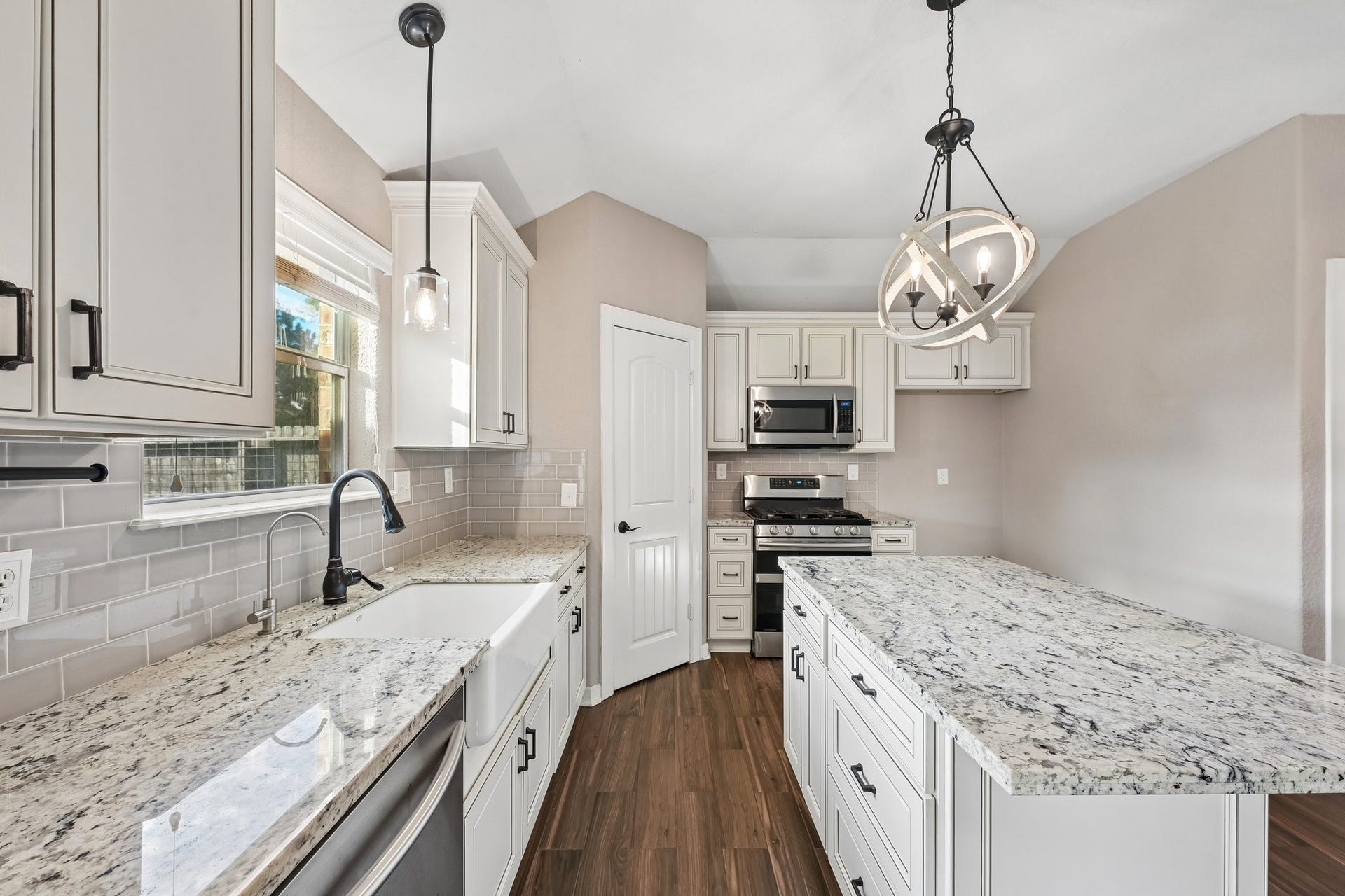 5012 Bayou Dr, Dickinson, TX 77539 Bright and inviting kitchen featuring elegant granite countertops, modern stainless steel appliances, and stylish pendant lighting, complemented by warm wood flooring.
