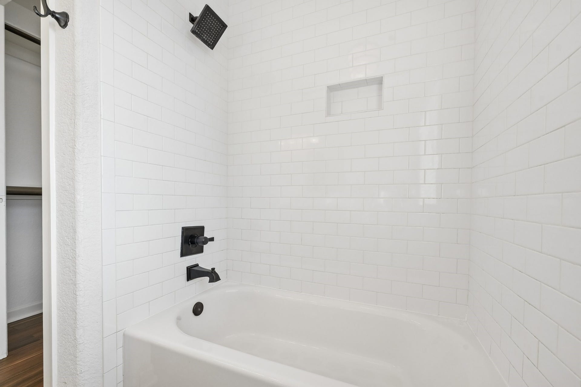 5012 Bayou Dr, Dickinson, TX 77539 Bright and modern bathroom featuring a sleek white subway tile design, complemented by matte black fixtures and a spacious tub for relaxation.