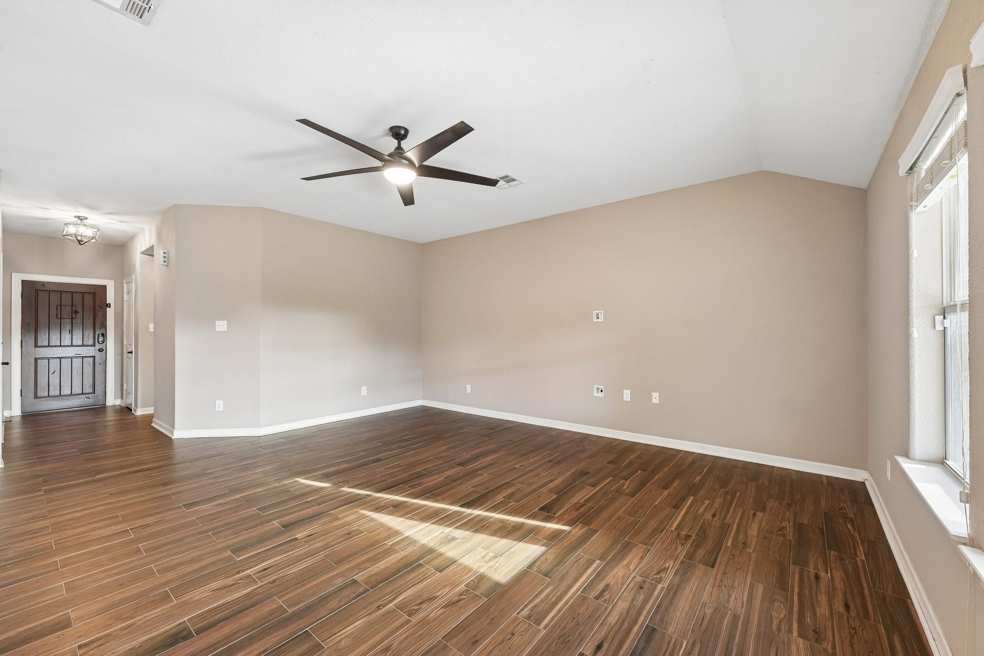 5012 Bayou Dr, Dickinson, TX 77539 Spacious living area with elegant wood-look flooring, neutral walls, and abundant natural light, complemented by a modern ceiling fan.
