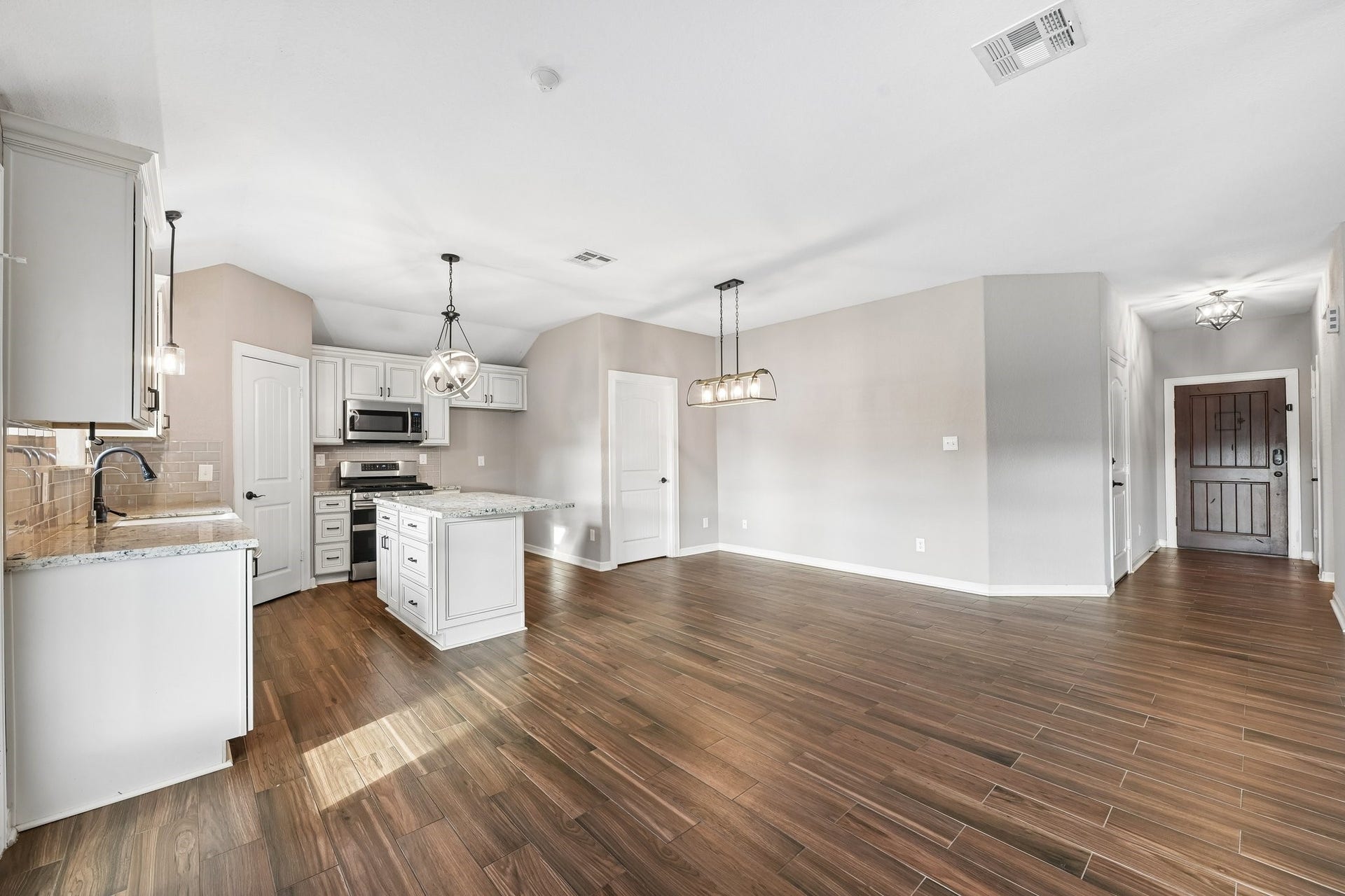 5012 Bayou Dr, Dickinson, TX 77539 Spacious open-concept kitchen and living area featuring elegant wood flooring, modern stainless steel appliances, and stylish pendant lighting, perfect for entertaining.