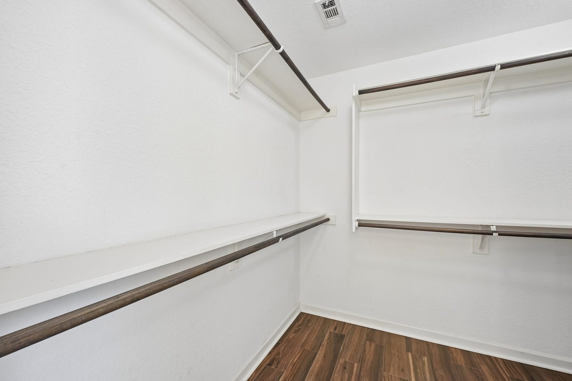 5012 Bayou Dr, Dickinson, TX 77539 Spacious walk-in closet featuring sleek wooden flooring and ample shelving for organized storage.