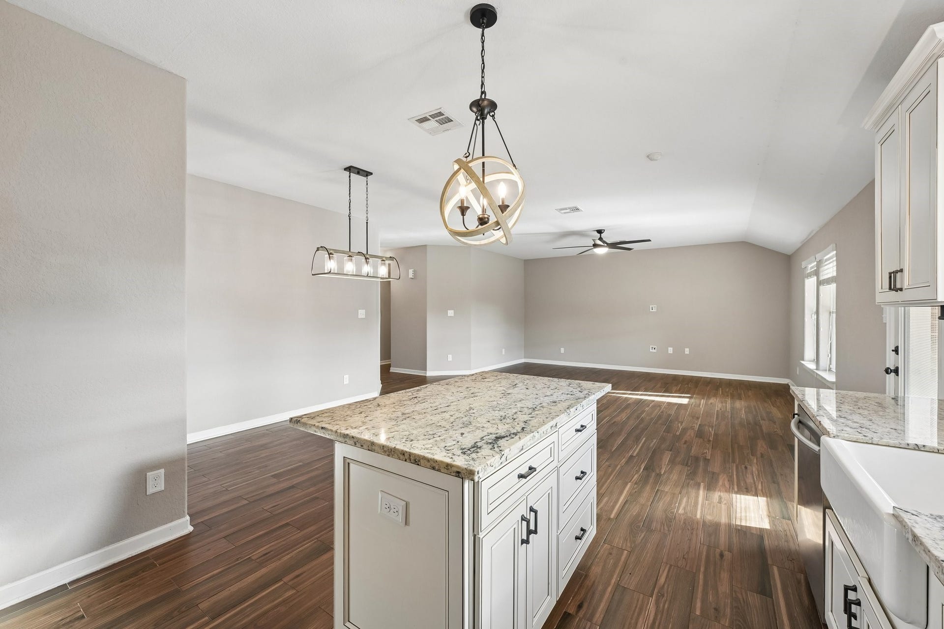 5012 Bayou Dr, Dickinson, TX 77539 Bright and spacious open-plan living area featuring elegant wood floors, a modern kitchen island with granite countertops, and stylish pendant lighting.