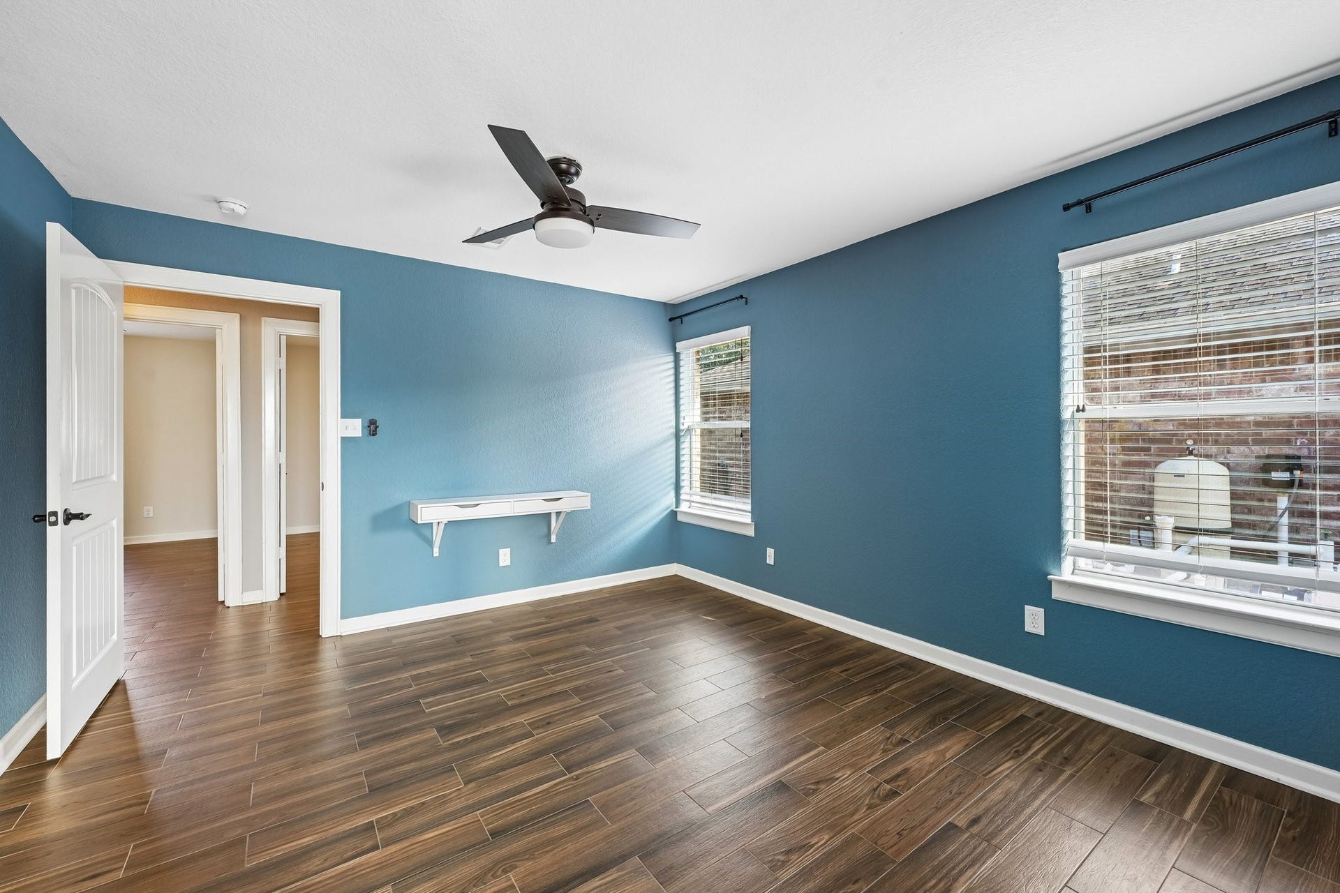 5012 Bayou Dr, Dickinson, TX 77539 Spacious bedroom with rich wood flooring, calming blue walls, and ample natural light from large windows.