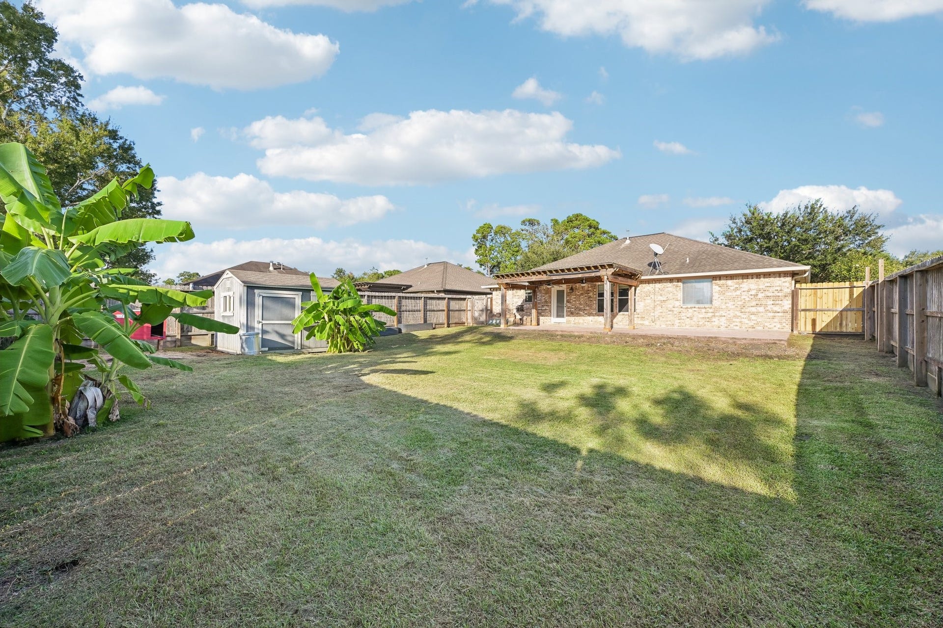 5012 Bayou Dr, Dickinson, TX 77539 Expansive backyard with lush greenery and a spacious covered patio, perfect for outdoor activities and relaxation.