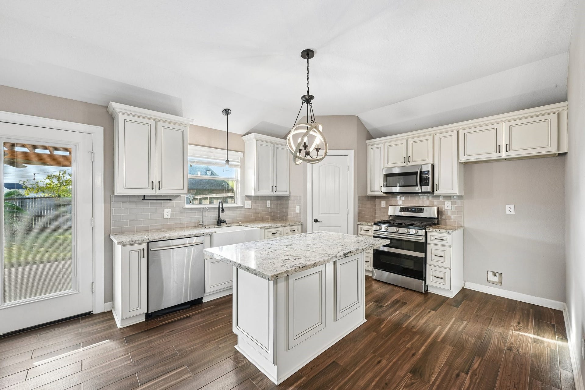 5012 Bayou Dr, Dickinson, TX 77539 Bright and inviting kitchen with modern stainless steel appliances, elegant white cabinetry, and a central island under stylish pendant lighting.