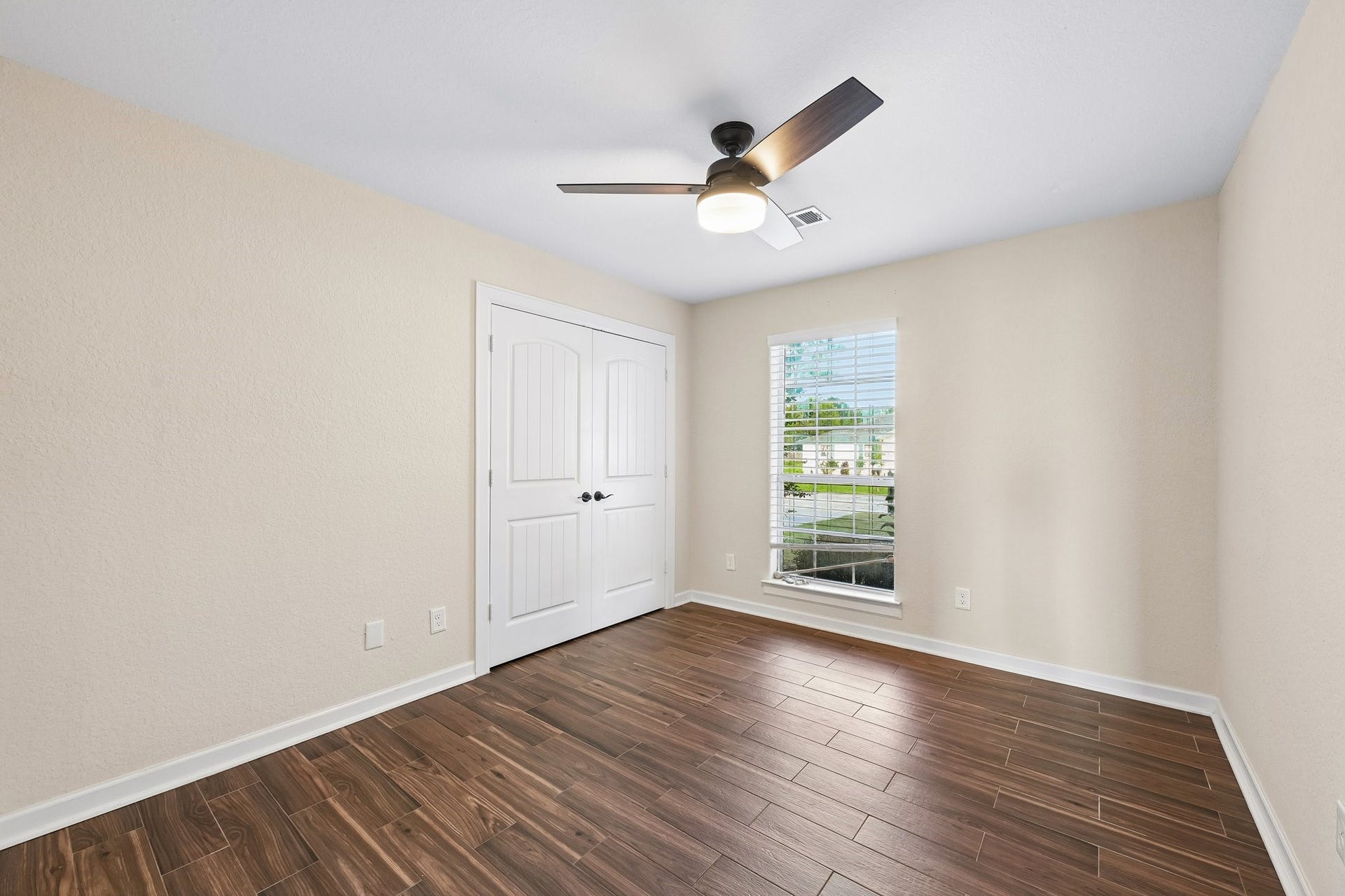 5012 Bayou Dr, Dickinson, TX 77539 Bright and airy room featuring elegant wood-look tile flooring, a modern ceiling fan, and a large window for natural light.