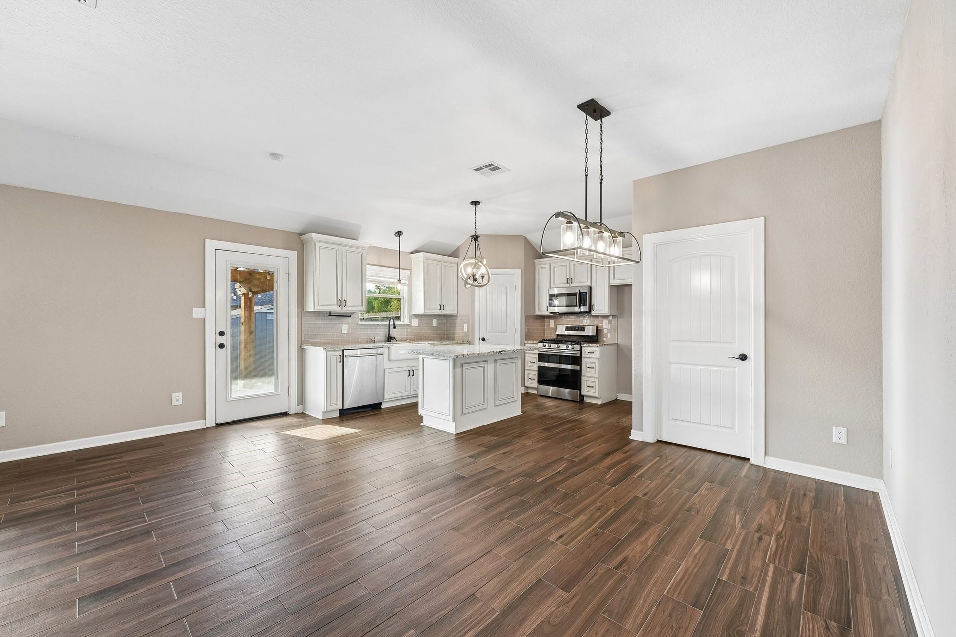 5012 Bayou Dr, Dickinson, TX 77539 Open-concept kitchen and dining area with elegant wood-look tile flooring, modern light fixtures, and a bright, airy feel.