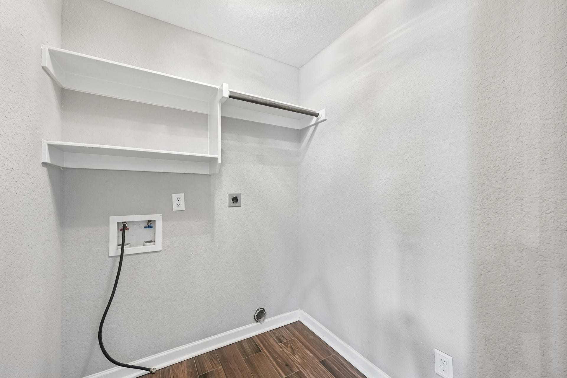 5012 Bayou Dr, Dickinson, TX 77539 Spacious laundry room with built-in shelves, hookups for washer and dryer, and sleek wood-look tile flooring.