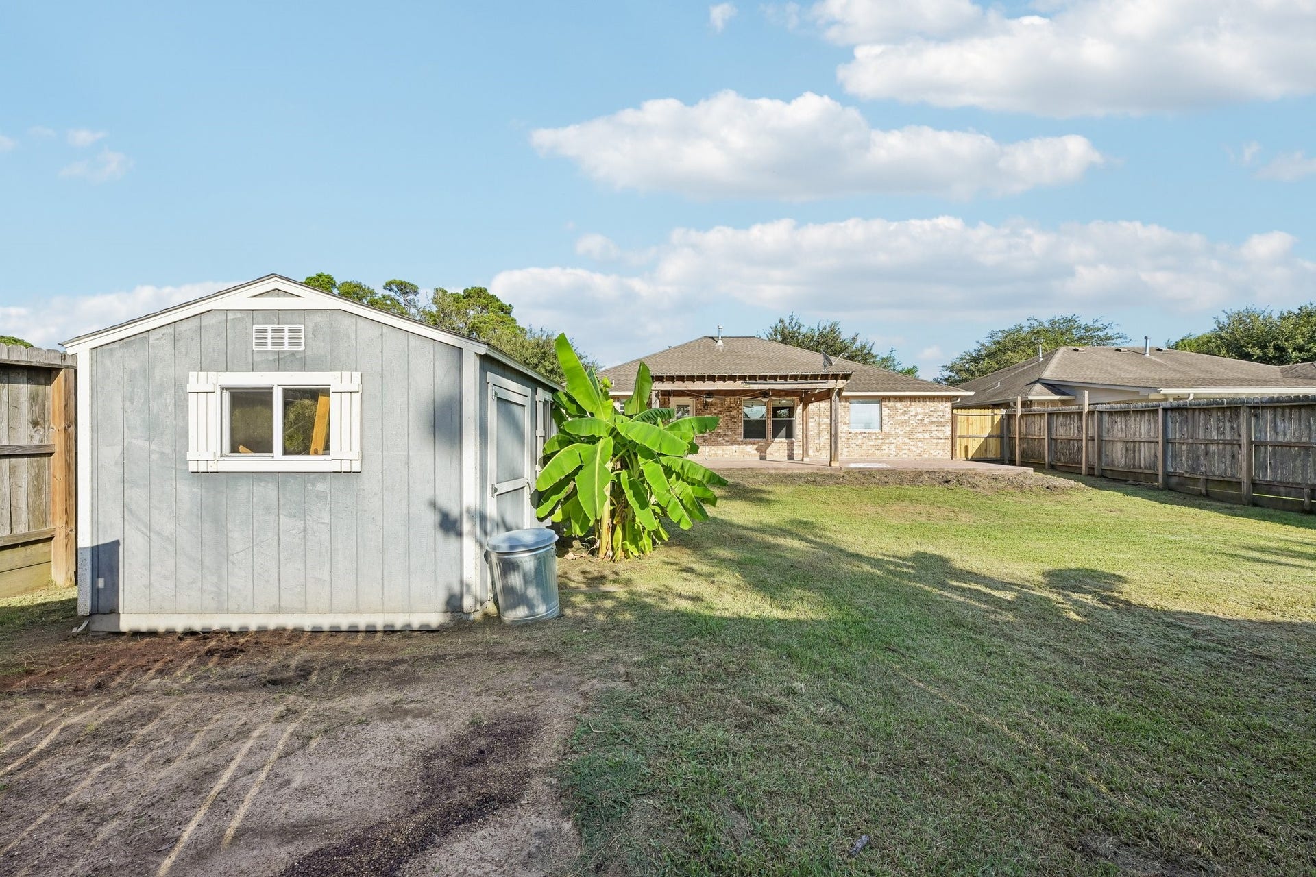 5012 Bayou Dr, Dickinson, TX 77539 Spacious backyard with a well-maintained lawn, convenient storage shed, and a clear view of the charming brick home, perfect for outdoor activities and relaxation.