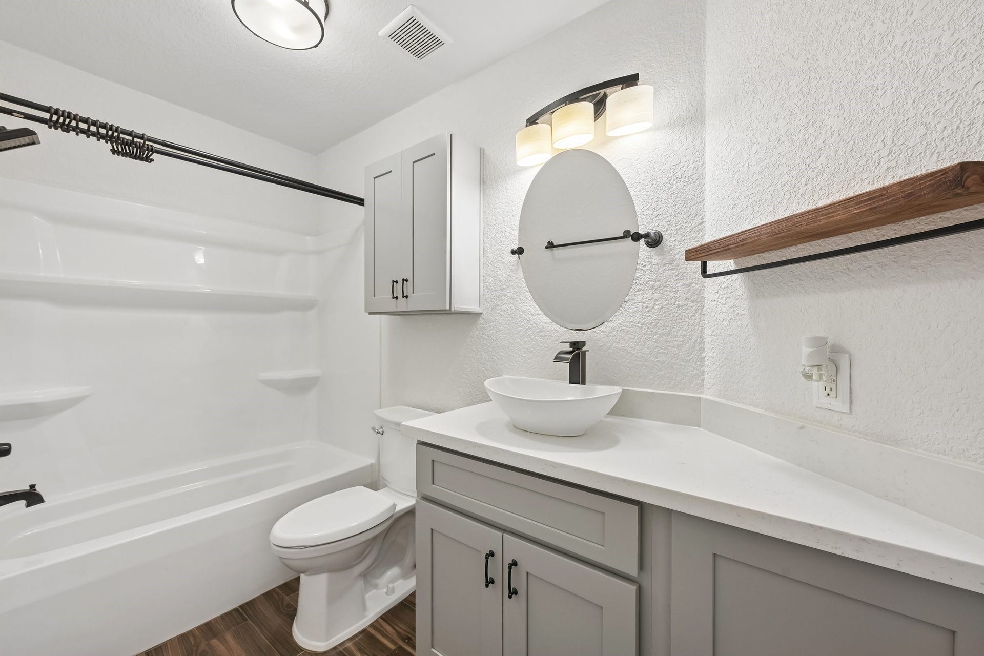 5012 Bayou Dr, Dickinson, TX 77539 Modern bathroom with elegant fixtures, featuring a sleek vessel sink, stylish round mirror, and a spacious bathtub with built-in shelving.