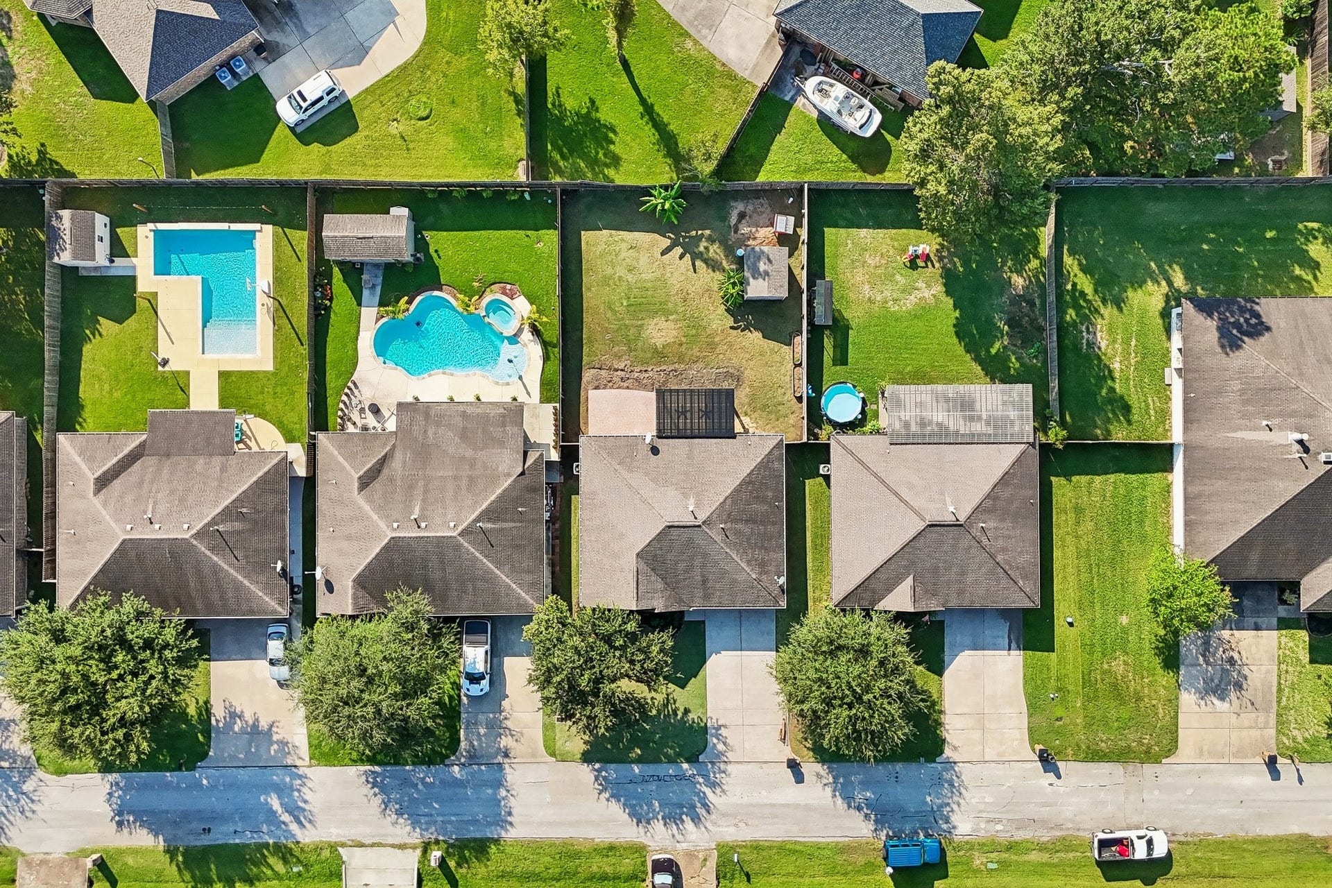 5012 Bayou Dr, Dickinson, TX 77539 Charming suburban homes with spacious backyards, some featuring inviting swimming pools, perfect for relaxation and entertaining.