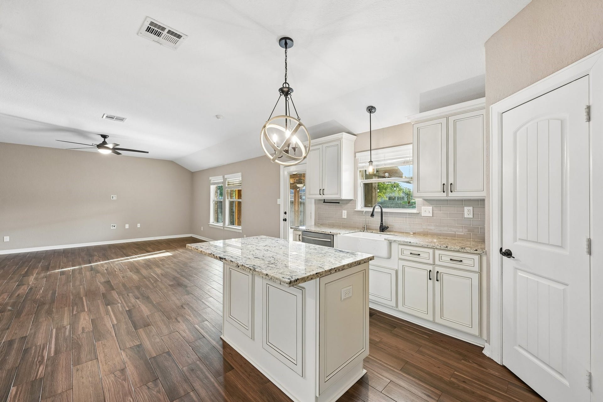 5012 Bayou Dr, Dickinson, TX 77539 Stunning open-concept kitchen and living area featuring elegant hardwood floors, a large island with granite countertops, modern pendant lighting, and ample cabinetry for storage.