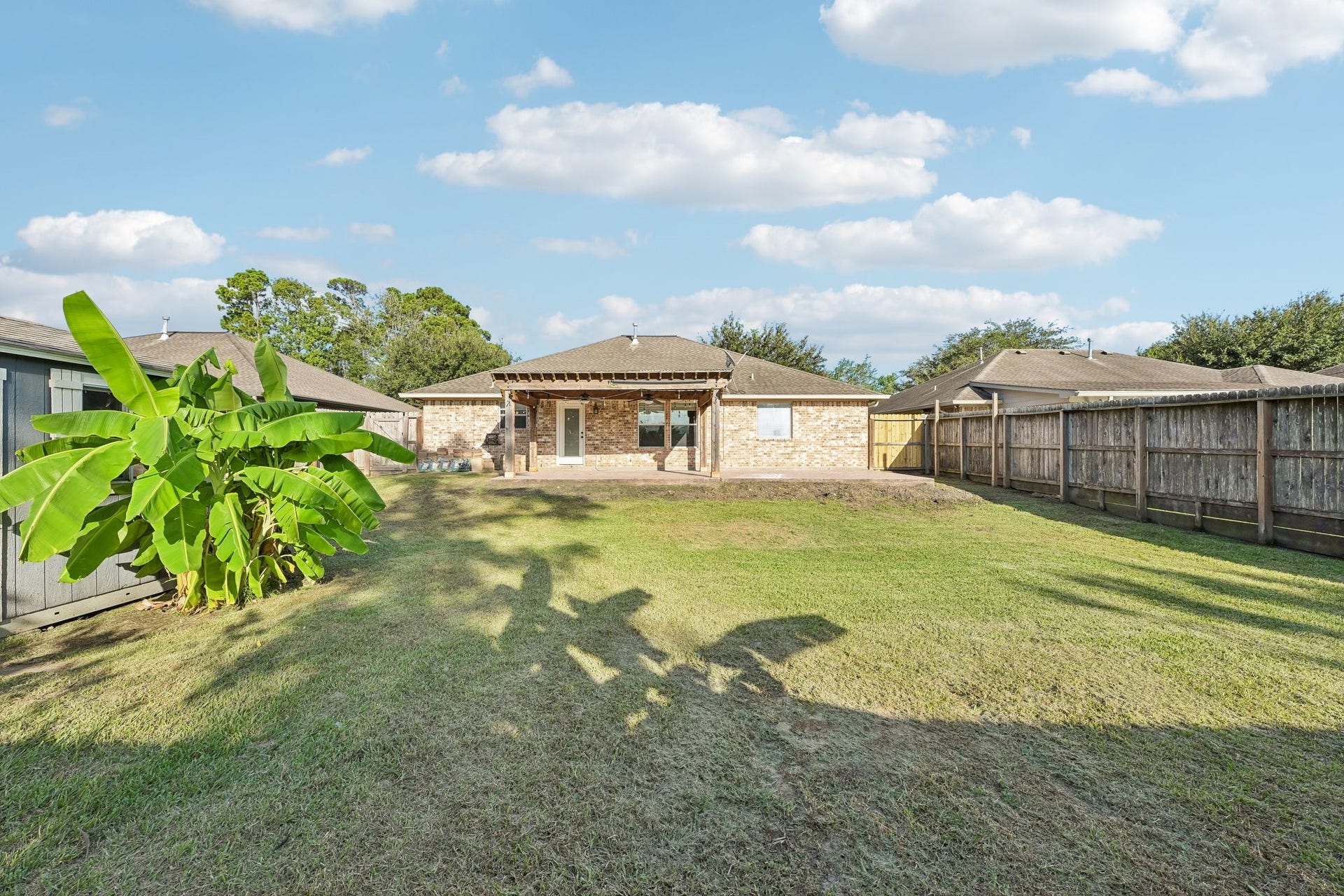 5012 Bayou Dr, Dickinson, TX 77539 Spacious backyard with well-maintained lawn, privacy fence, and a charming brick exterior, perfect for outdoor activities and gatherings.