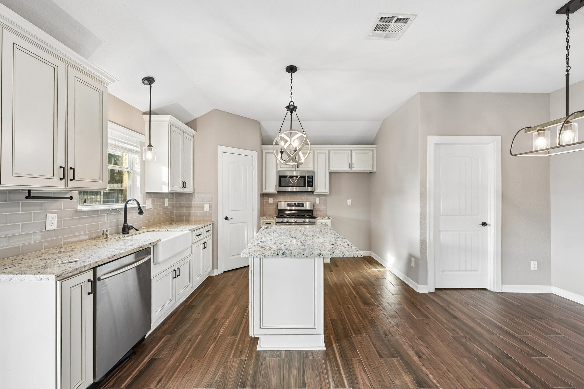 5012 Bayou Dr, Dickinson, TX 77539 Elegant kitchen with modern stainless steel appliances, granite countertops, and a central island. Features sleek cabinetry, wood-look tile flooring, and stylish pendant lighting for a welcoming atmosphere.