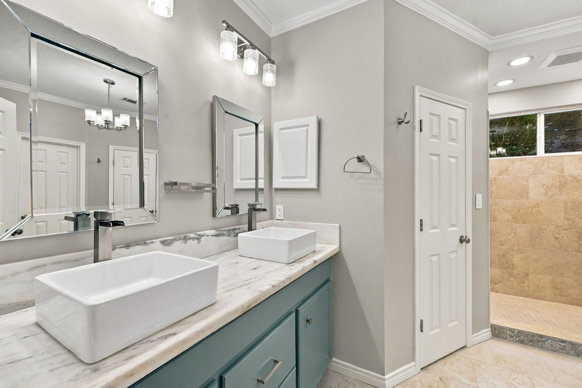 1430 Stependale Drive, Katy, TX 77450 Contemporary bathroom with dual vessel sinks, a teal vanity, elegant mirrors, and a spacious walk-in shower.