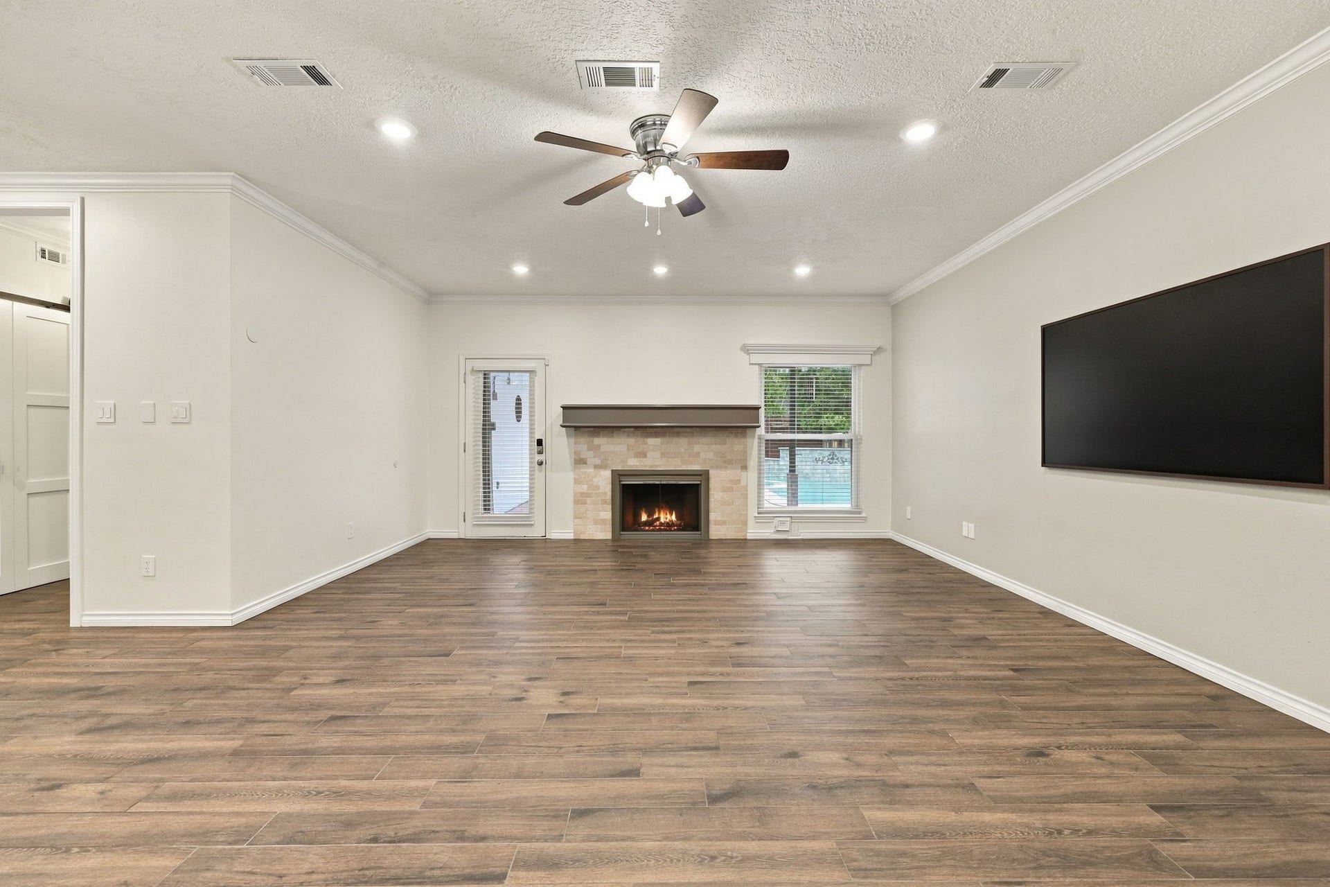 1430 Stependale Drive, Katy, TX 77450 Spacious living room with wood-look flooring, recessed lighting, a fireplace, and a large wall-mounted TV.