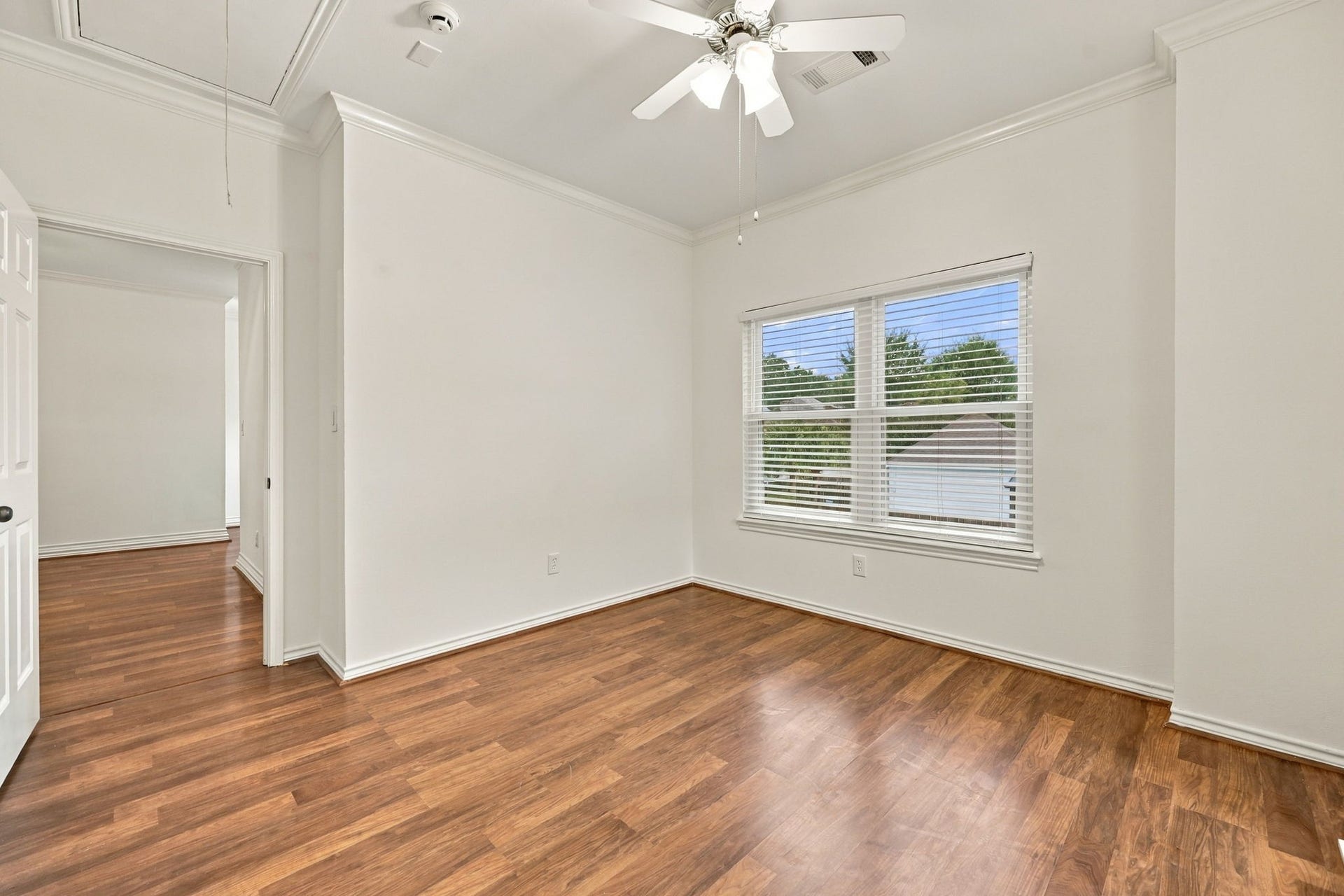 1430 Stependale Drive, Katy, TX 77450 Spacious bedroom with wood-look flooring, ceiling fan, built-in shelving, and multiple windows providing natural light.