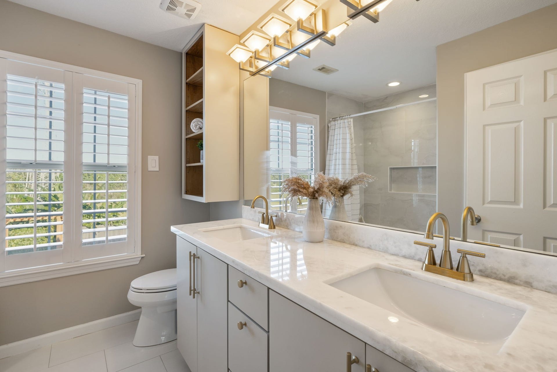 236 Sunset Ridge Drive, League City, TX 77573 Elegant hallway bathroom featuring a dual-sink vanity with sleek marble countertops and gold fixture