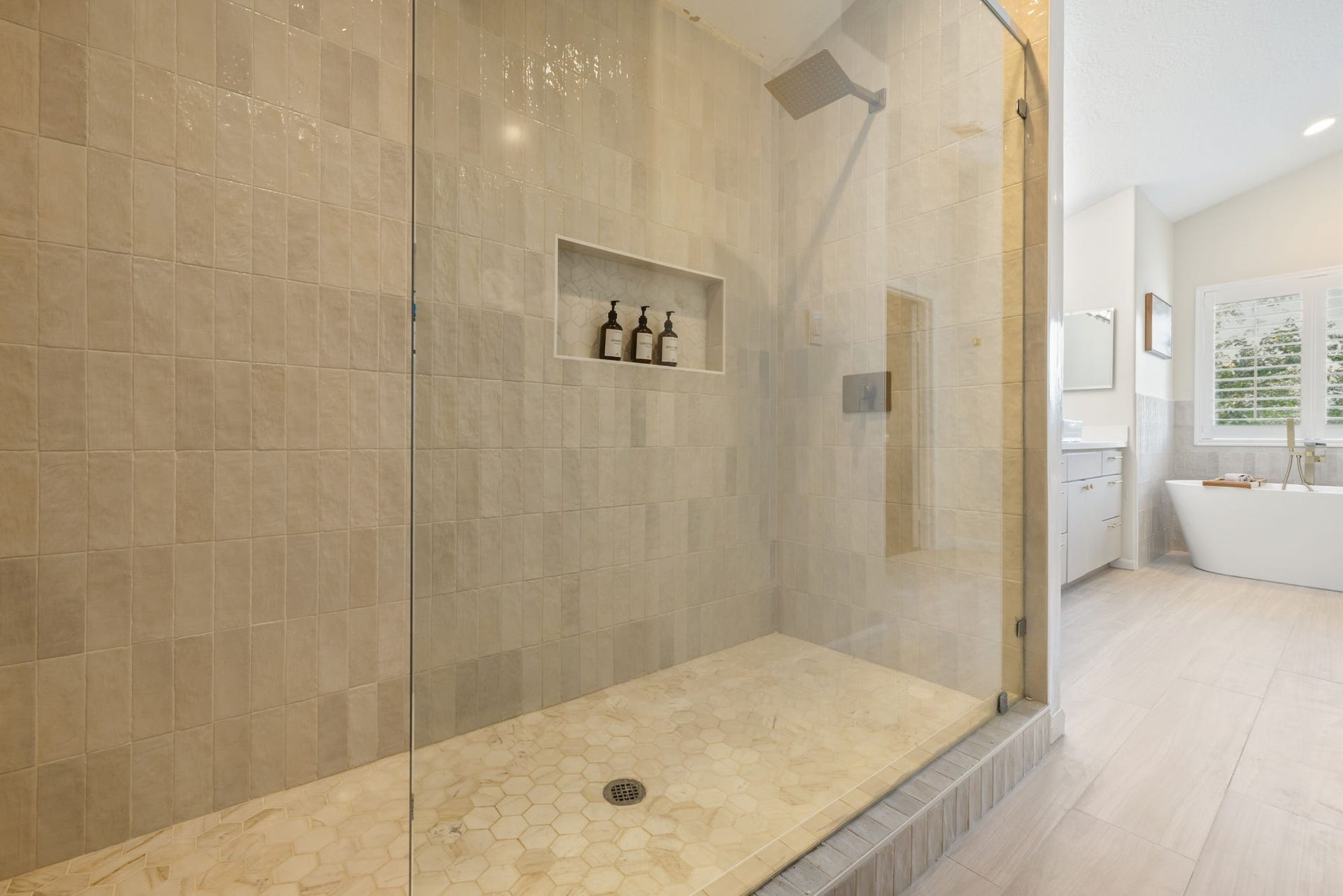 236 Sunset Ridge Drive, League City, TX 77573 Oversized walk-in shower with floor-to-ceiling tile, glass enclosure, rainfall showerhead, and recessed storage niche. There is also built-in cabinets directly across from the shower for additional linen storage.