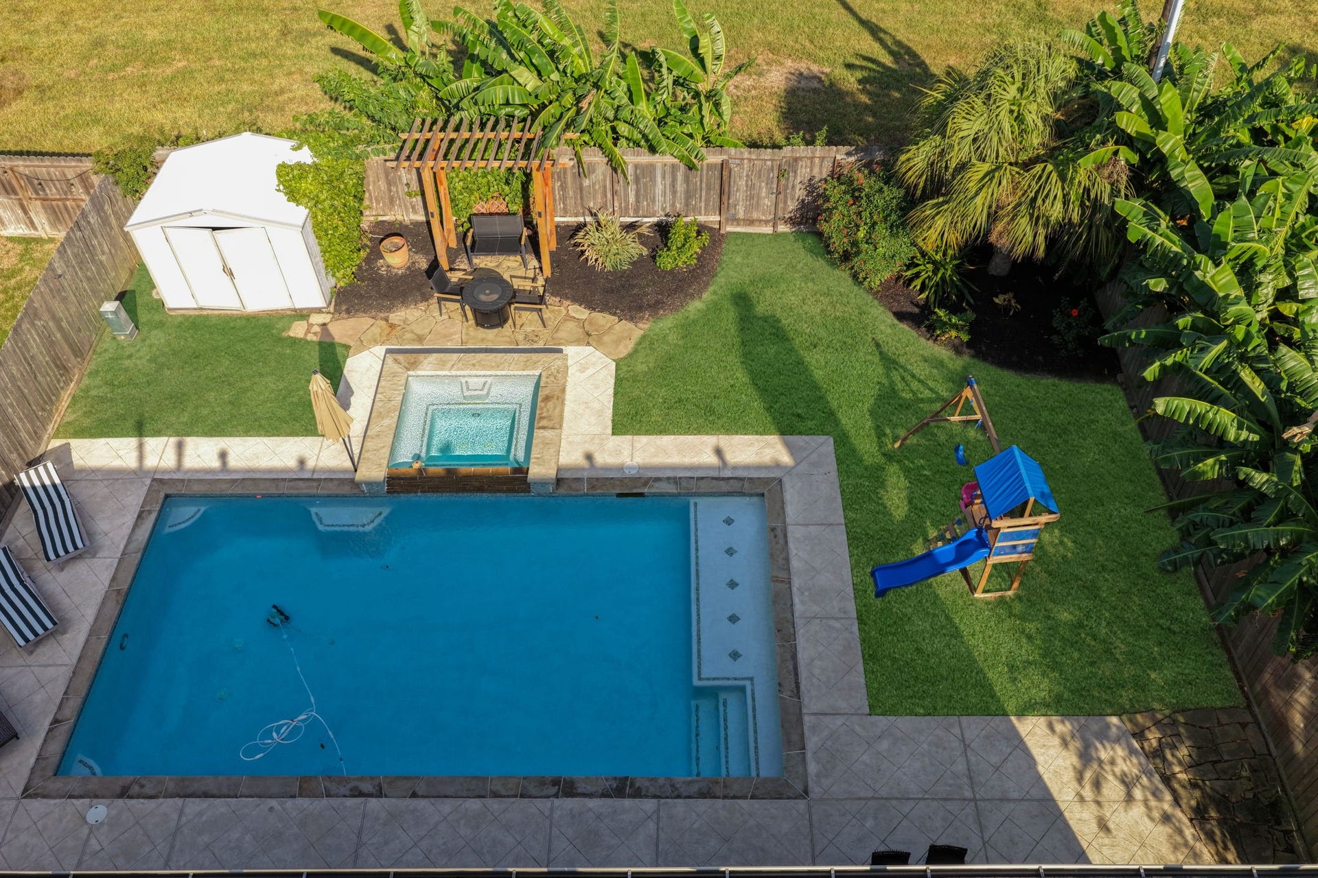 236 Sunset Ridge Drive, League City, TX 77573 Bird's eye view of the beautifully designed outdoor space featuring a pool and hot tub, pergola seating area, tropical landscaping, and generous green space, all with the added privacy of no back neighbors.