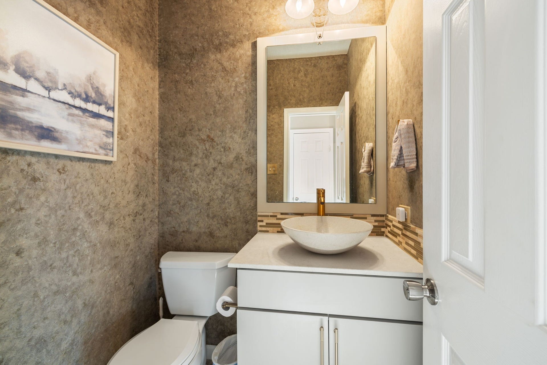 236 Sunset Ridge Drive, League City, TX 77573 Stylish first-floor powder room with a contemporary vessel sink, decorative tile accents, and warm textured walls.