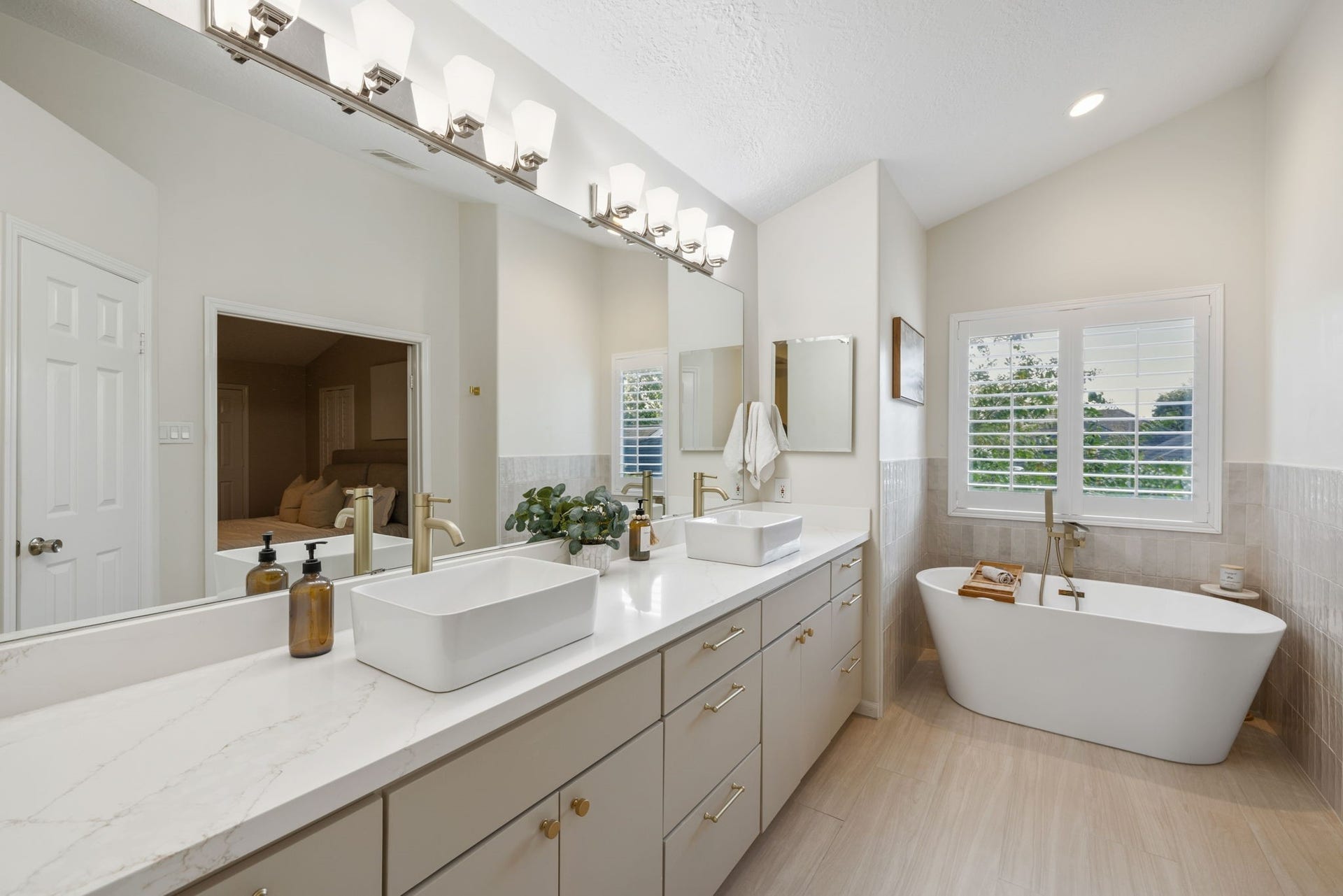 236 Sunset Ridge Drive, League City, TX 77573 Beautifully updated primary bath featuring dual vessel sinks, a freestanding soaking tub, and sophisticated gold-tone fixtures.
