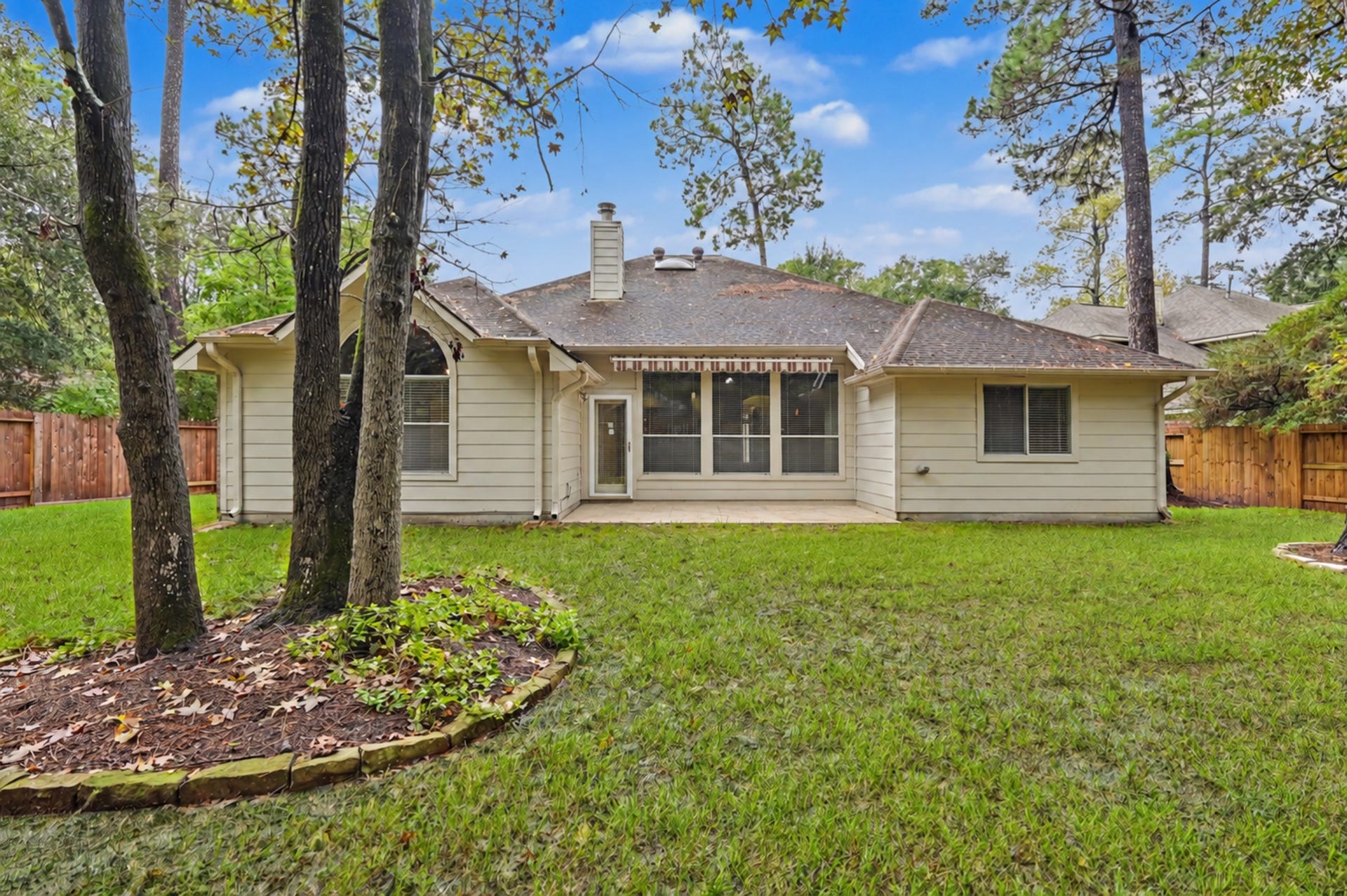 26 N Brooksedge Circle, The Woodlands, TX 77382 Outside, the mature trees and patio with retractable awning makes the backyard an easy extension of the living space.