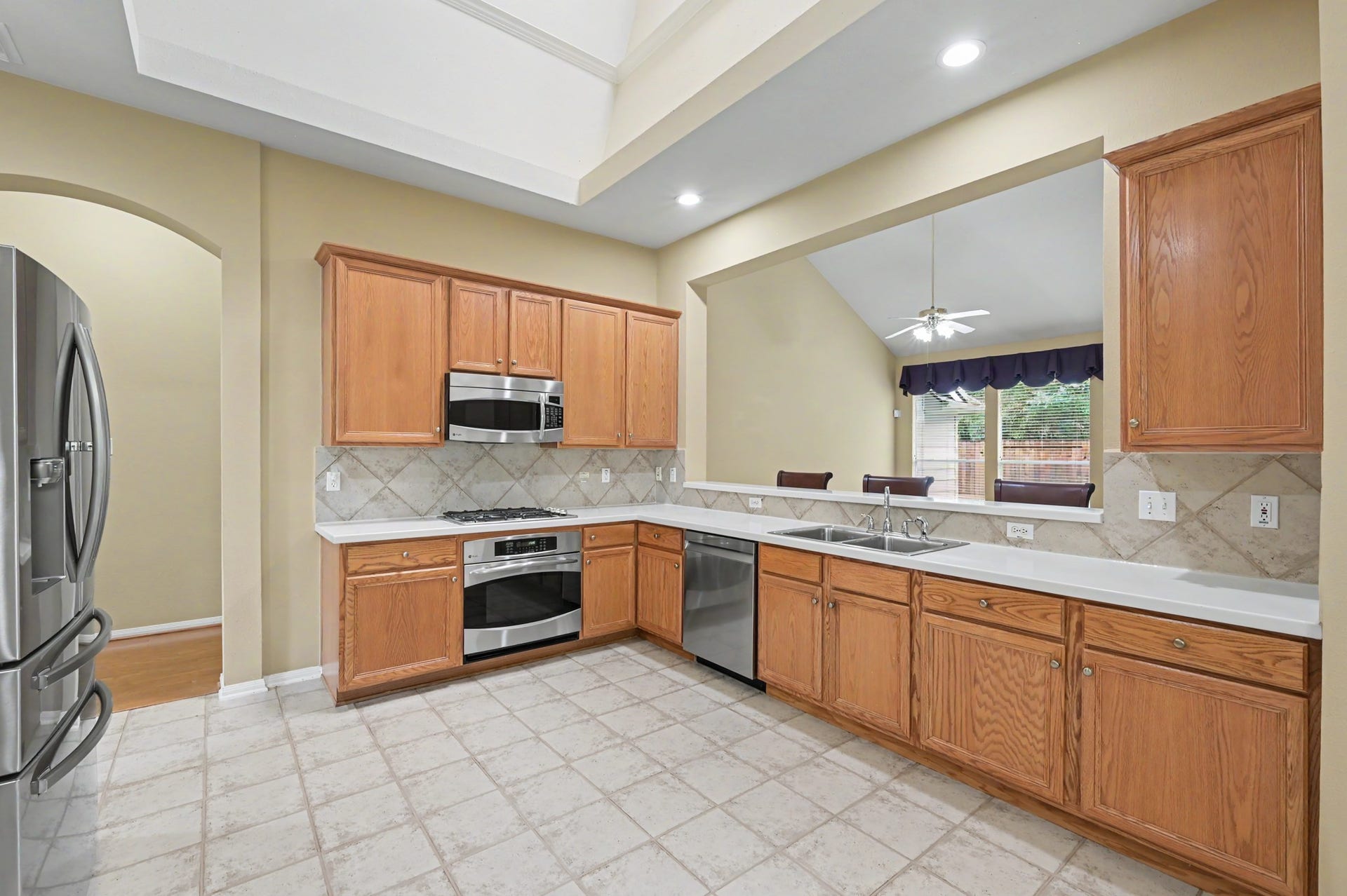 26 N Brooksedge Circle, The Woodlands, TX 77382 The heart of the home is the kitchen featuring a tiered ceiling and large skylight, gas cooktop, and plenty of prep and storage space. Pass through window to the den.