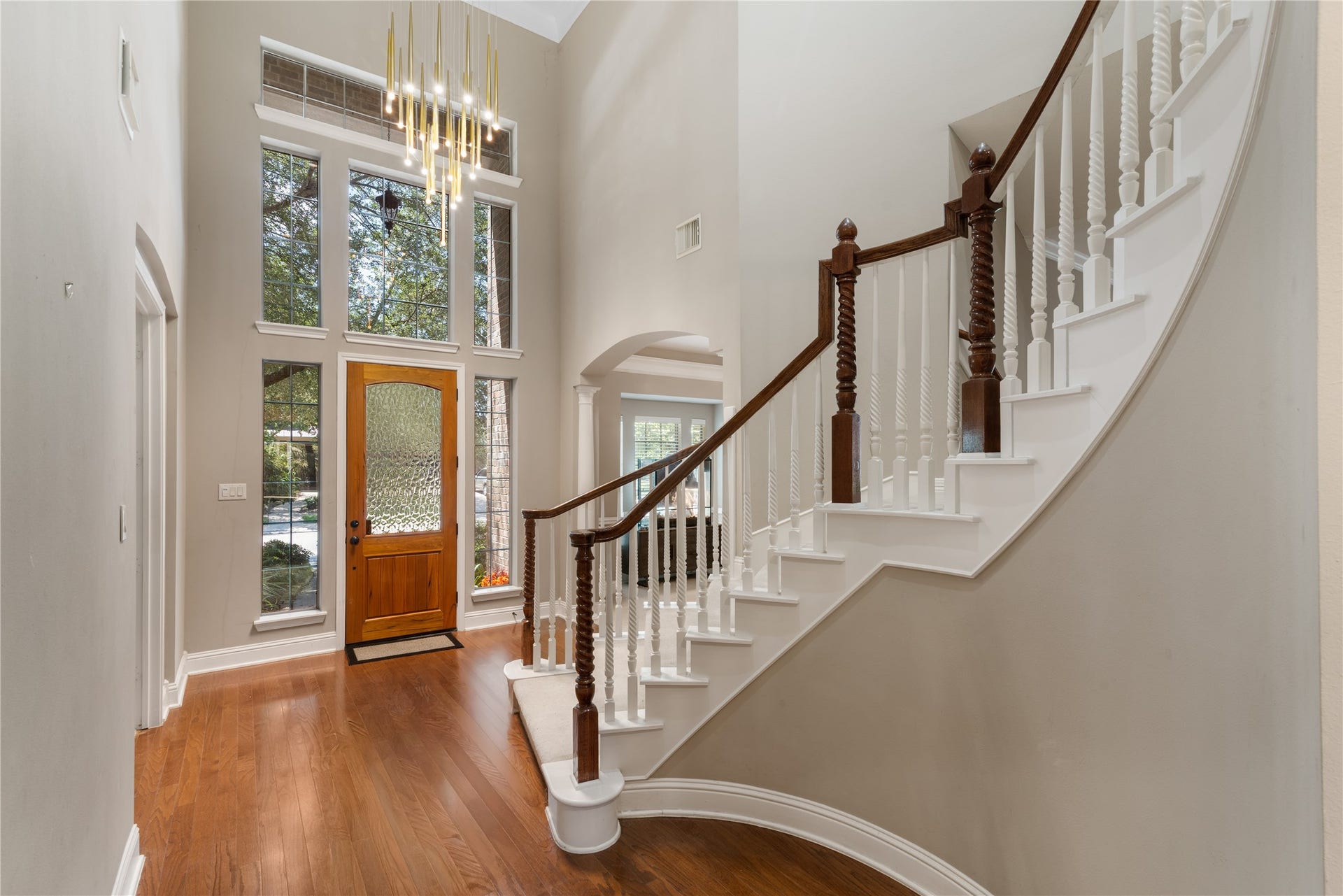 2525 W Ranch Drive, Friendswood, TX 77546 Stunning foyer with soaring ceilings, wood front door with decorative glass, tall surrounding windows fills the space with natural light, and a modern chandelier adds a luxurious touch.
